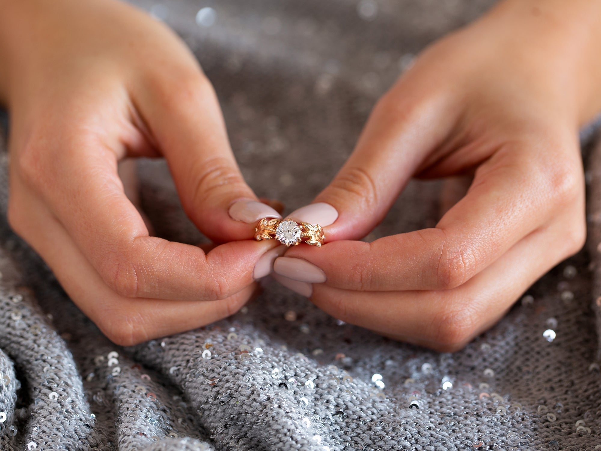 אישה מחזיקה טבעת יהלום מיוחדת בעיצוב עלים בזהב אדום