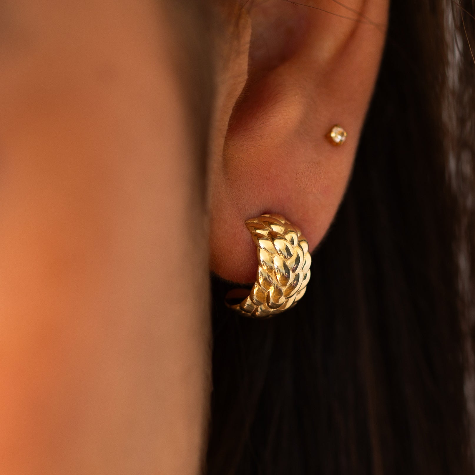 תקריב של אוזן של אישה שעונדת עגיל חישוק זהב