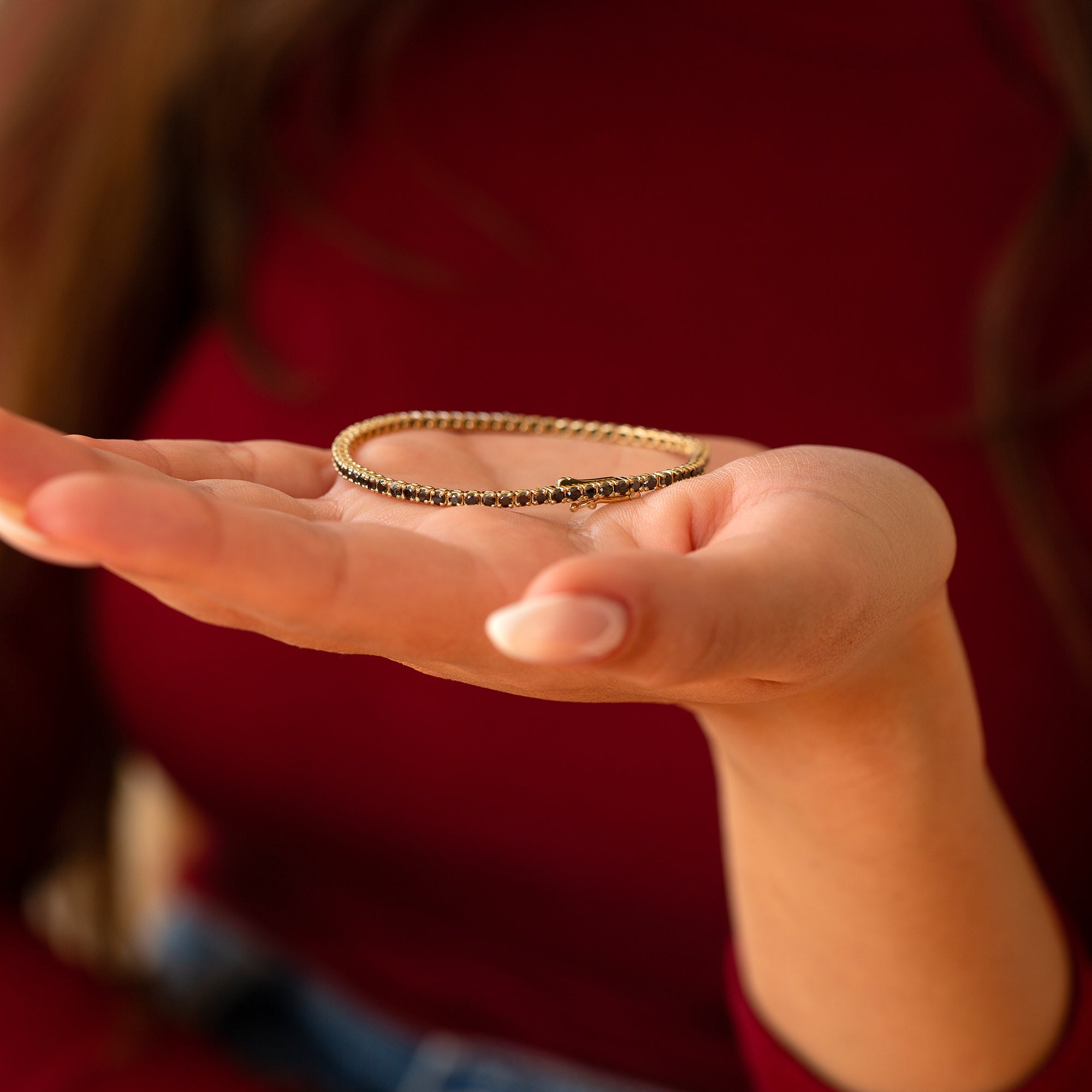 יד של אישה שמחזיקה צמיד טניס יהלומים שחורים