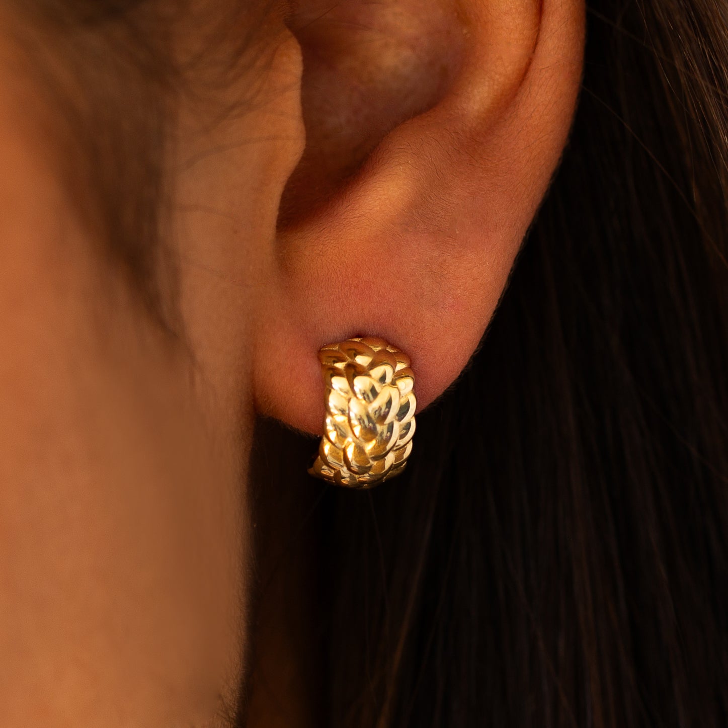 תקריב של אוזן של אישה שעונדת עגיל זהב 14J חישוק רחב