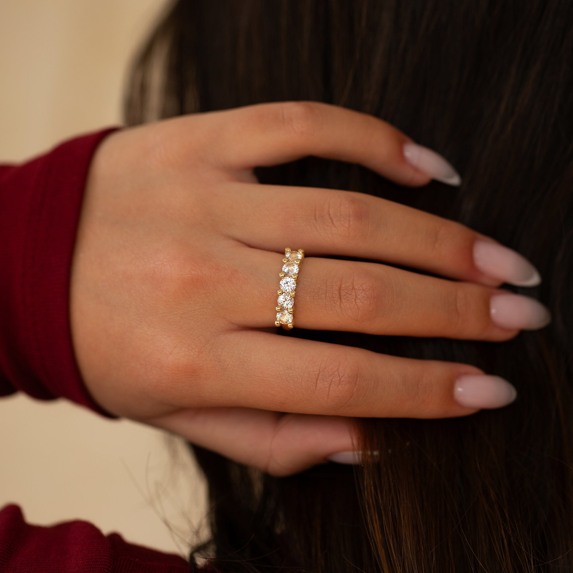 יד של אישה עונדת טבעת זהב 14 קראט משובצת אבני חן ורודות