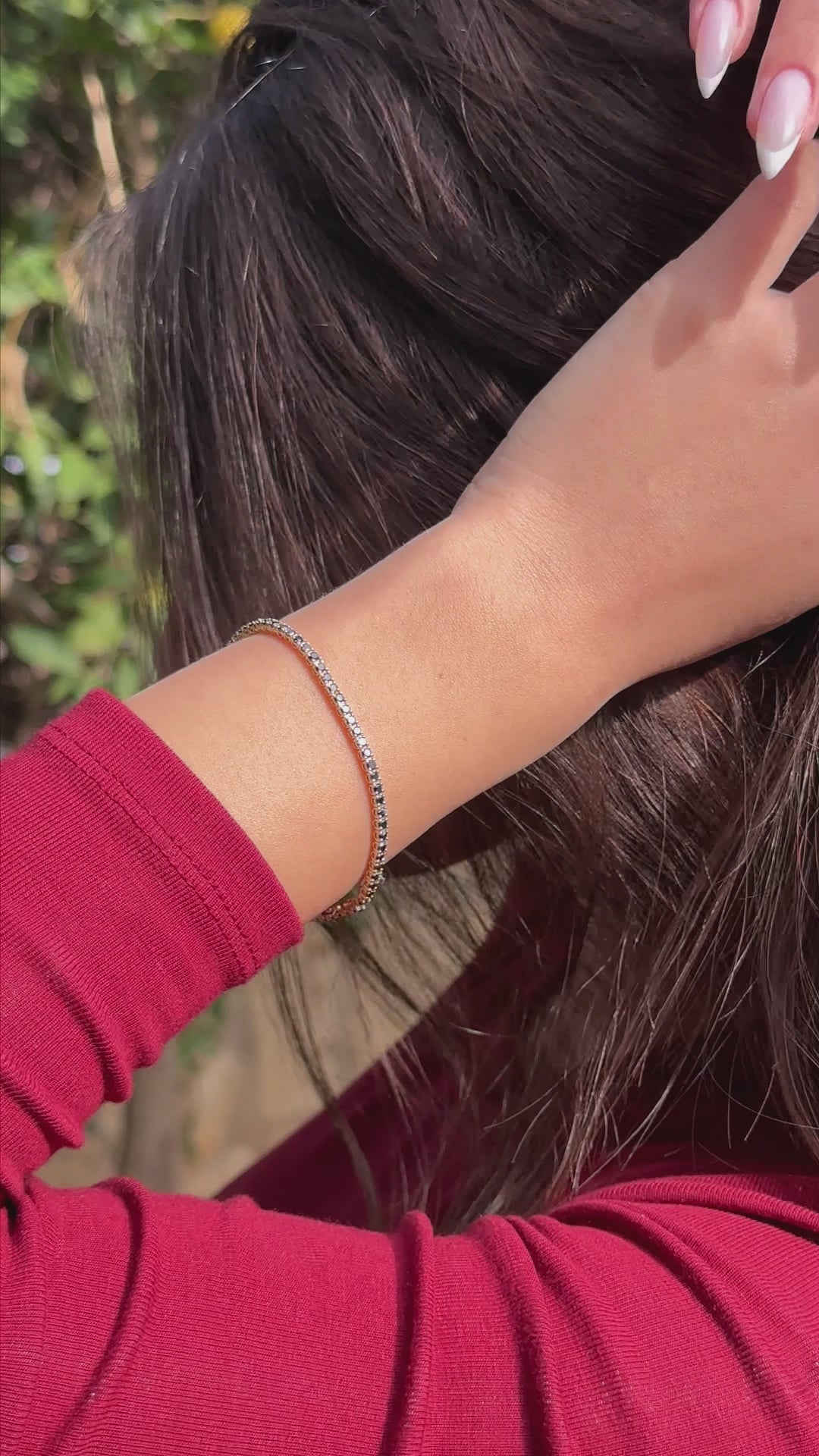 אישה עונדת צמיד טניס יהלומים שחורים וחולצה אדומה