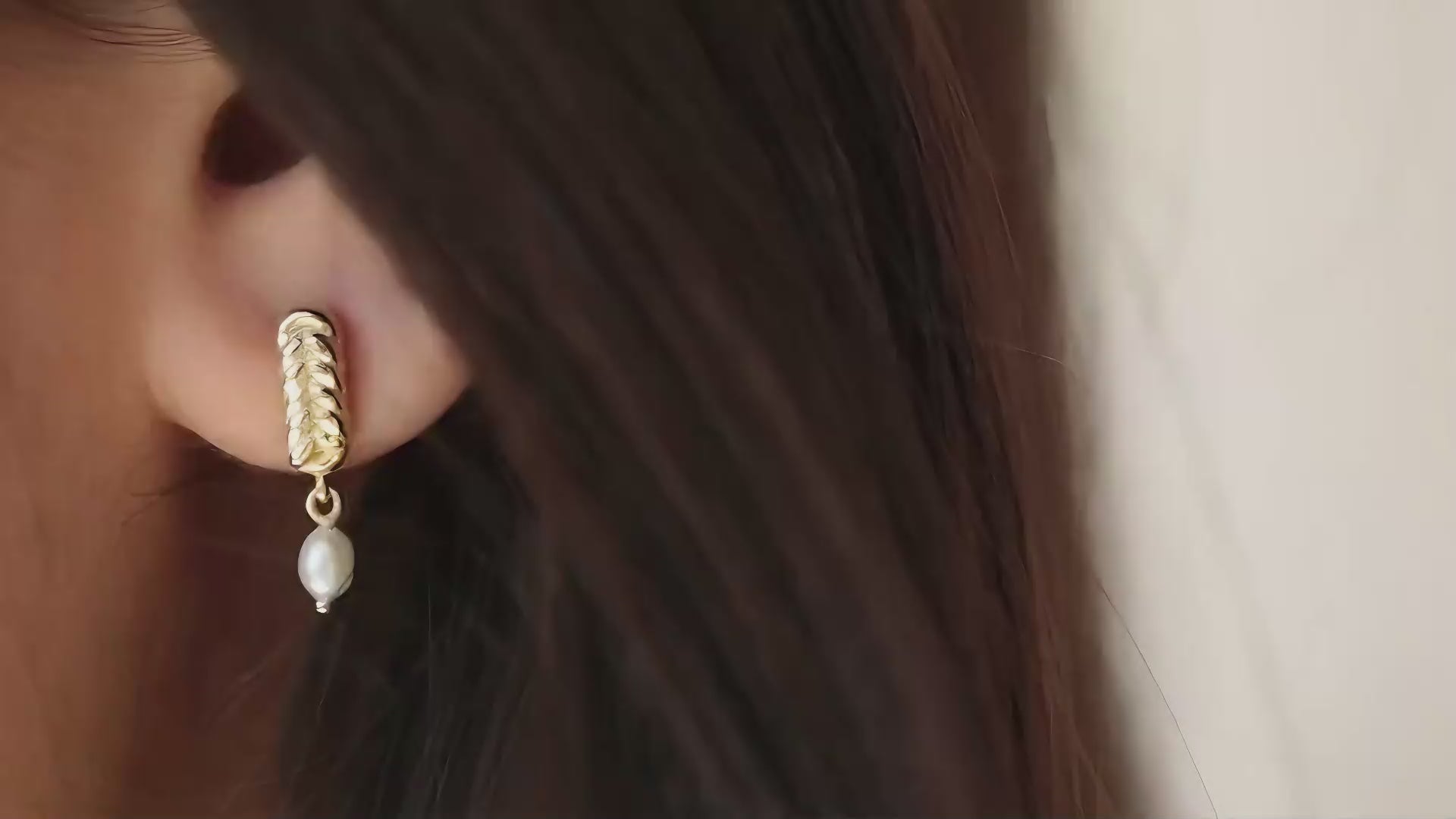 תקריב של אישה שעונדת עגילי פנינה נופלים מזהב צהוב 14K