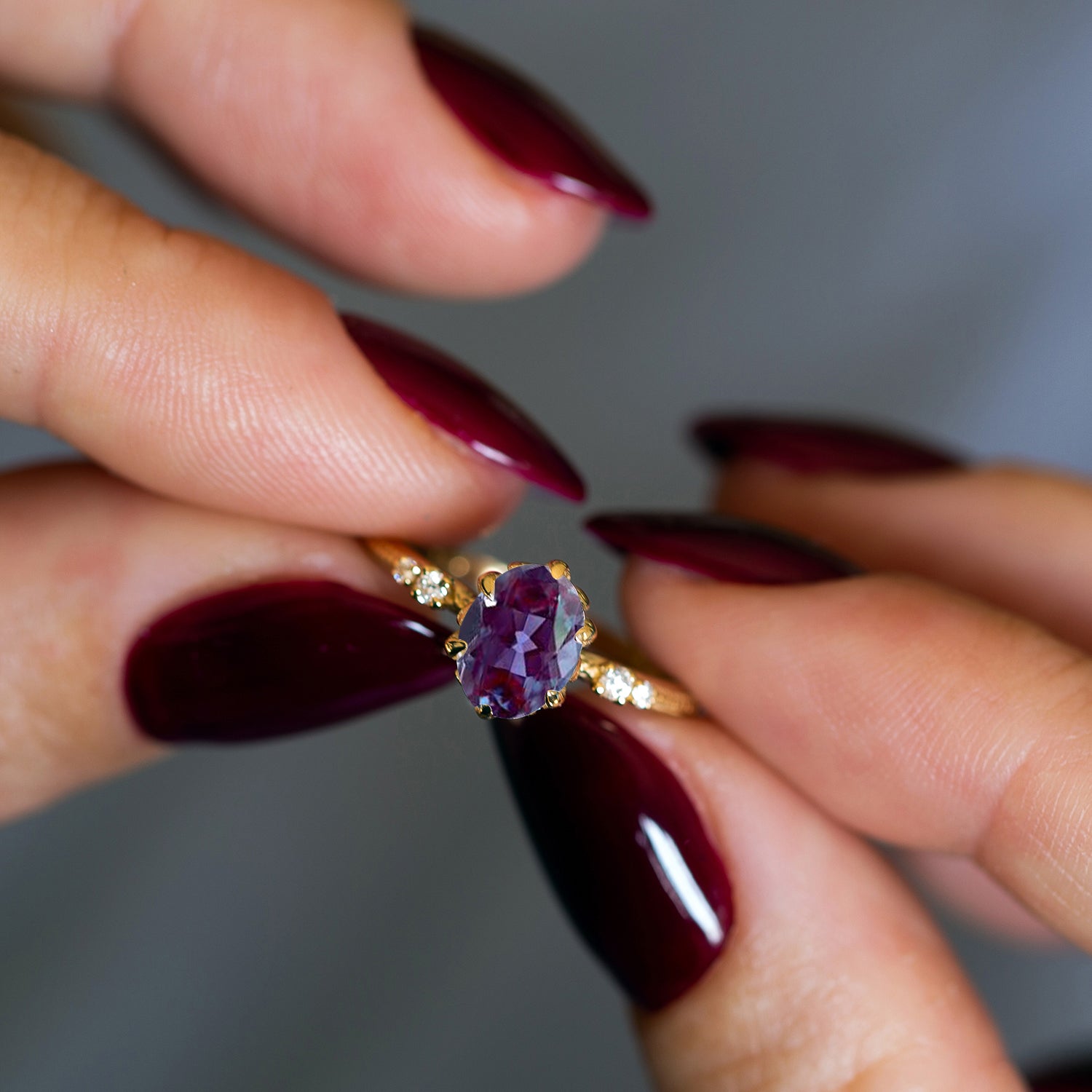 יד של אישה מחזיקה טבעת משובצת אבן חן סגולה ויהלומים