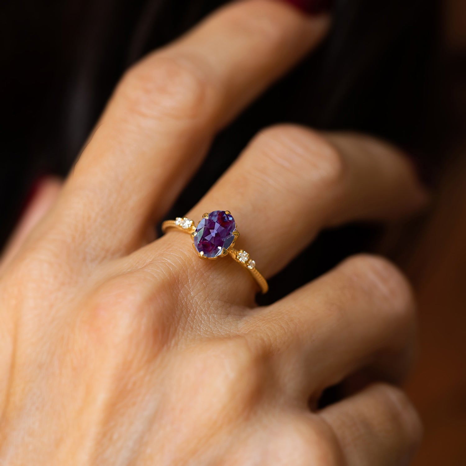 יד של אישה שעונדת טבעת זהב צהוב משובצת אבן חן כחולה אלכסנדריט