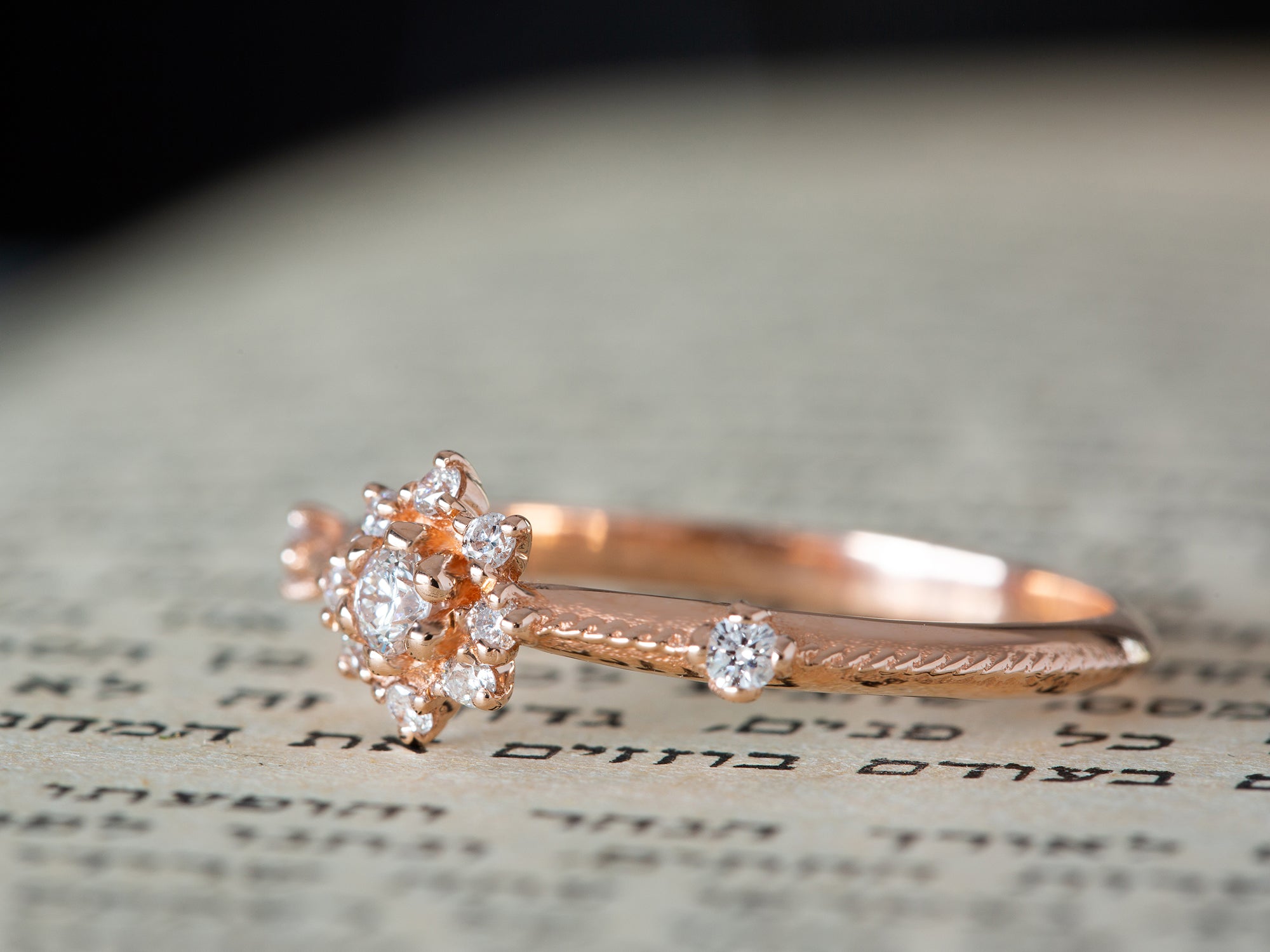 טבעת פרח יהלומים בזהב ורוד על רקע של ספר