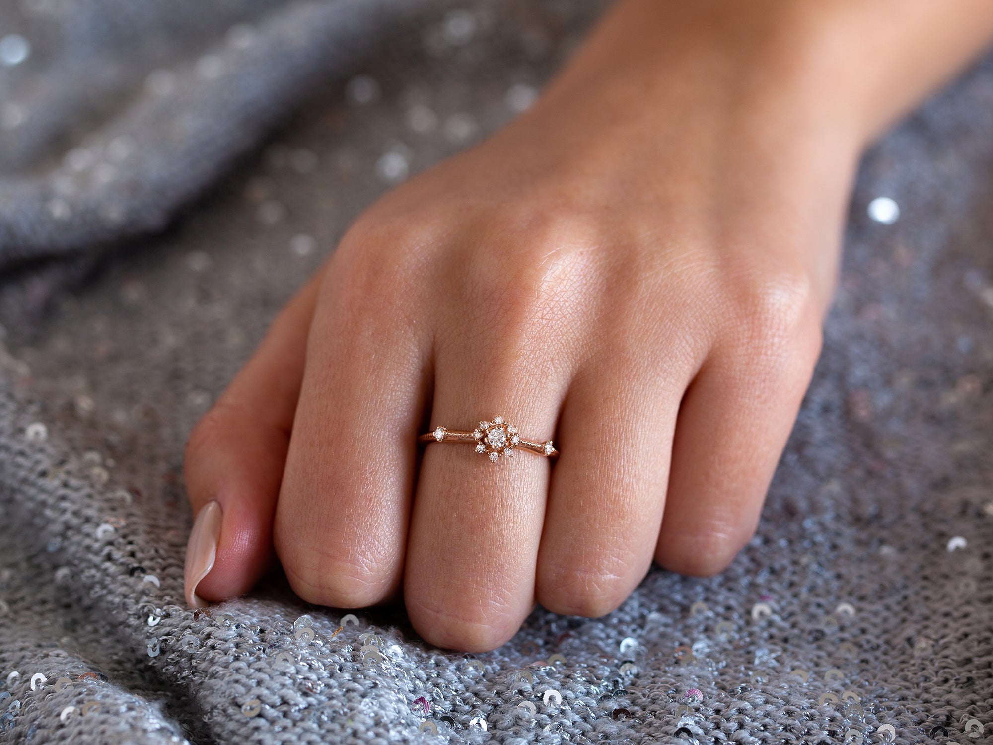 יד של אישה שעונדת טבעת כוכב בשיבוץ יהלומים טבעיים על רקע אפור