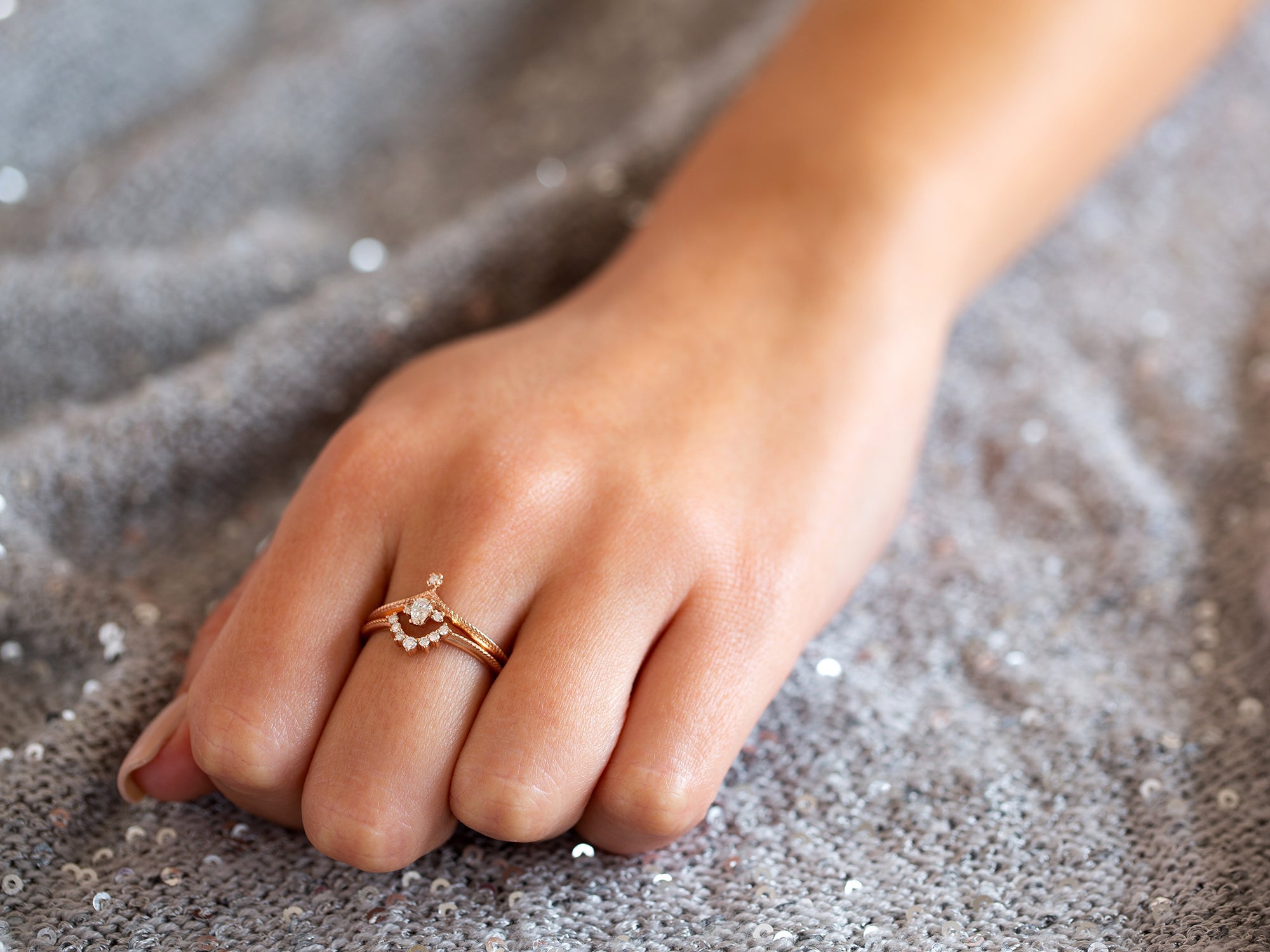 יד של אישה שעונדת סט טבעות זהב אדום משובצות יהלומים טבעיים