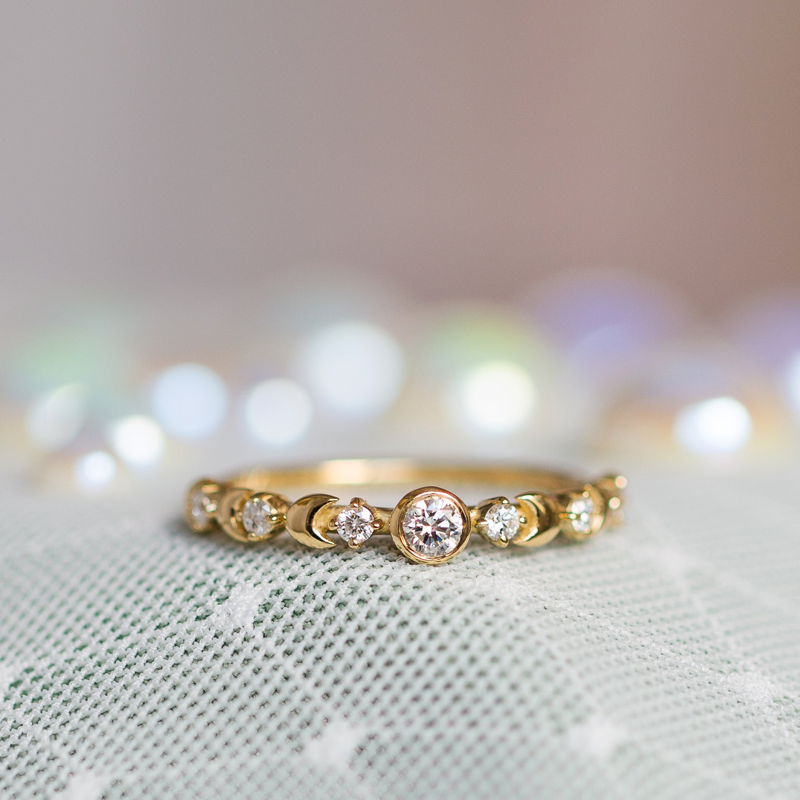 טבעת ירח מזהב צהוב משובצת אבני חן לבנות עם רקע מטושטש