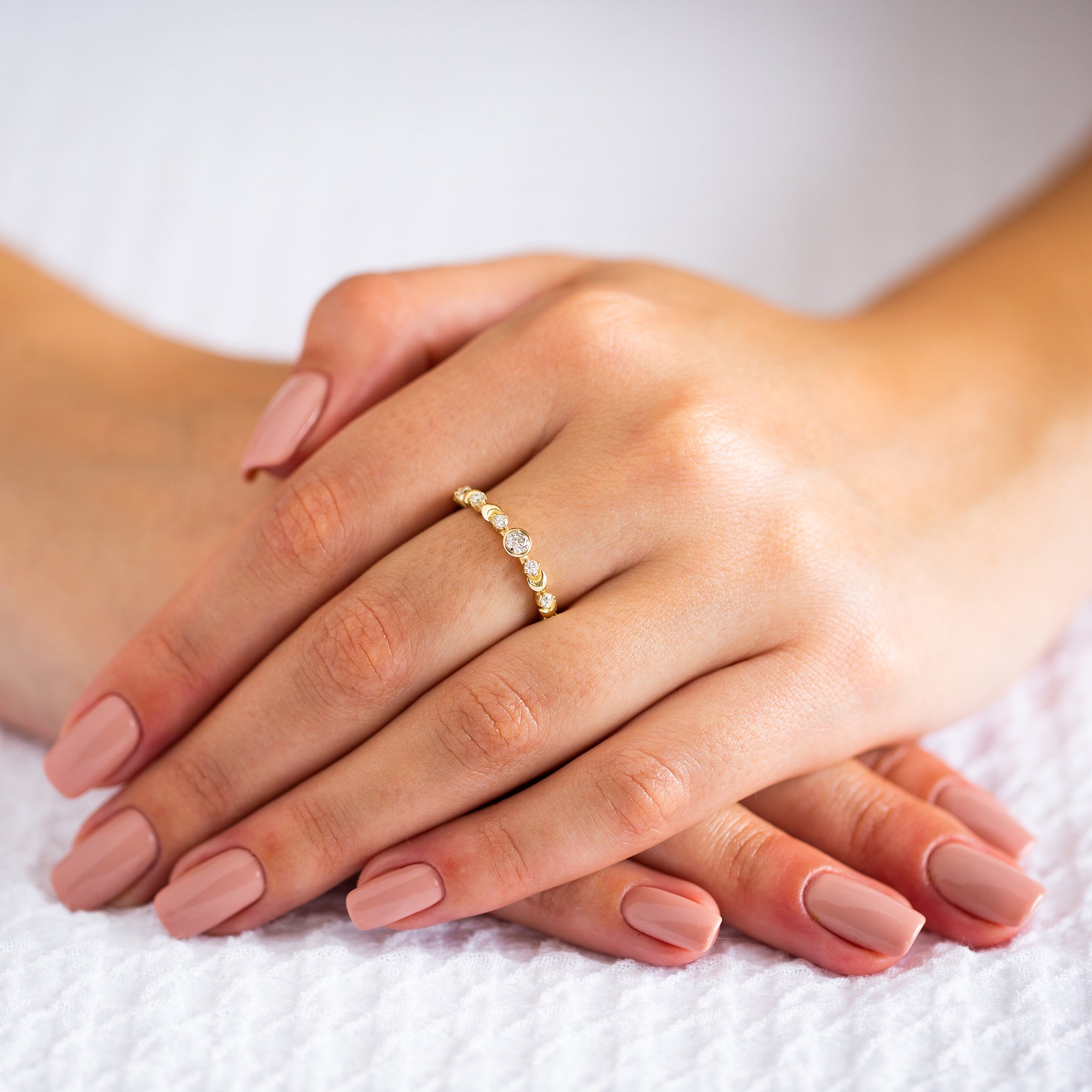 ידיים של אישה שעונדת טבעת זהב עדינה משובצת יהלומים לבנים