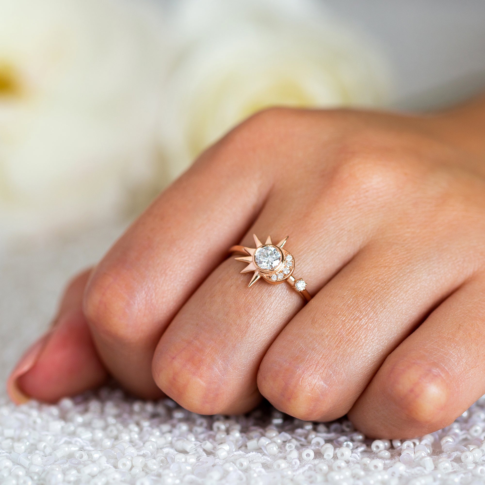 אישה עונדת טבעת מואסנייט מיוחדת עשויה זהב אדום 14 קראט משובצת יהלומים בעיצוב קסום של ירח ושמש