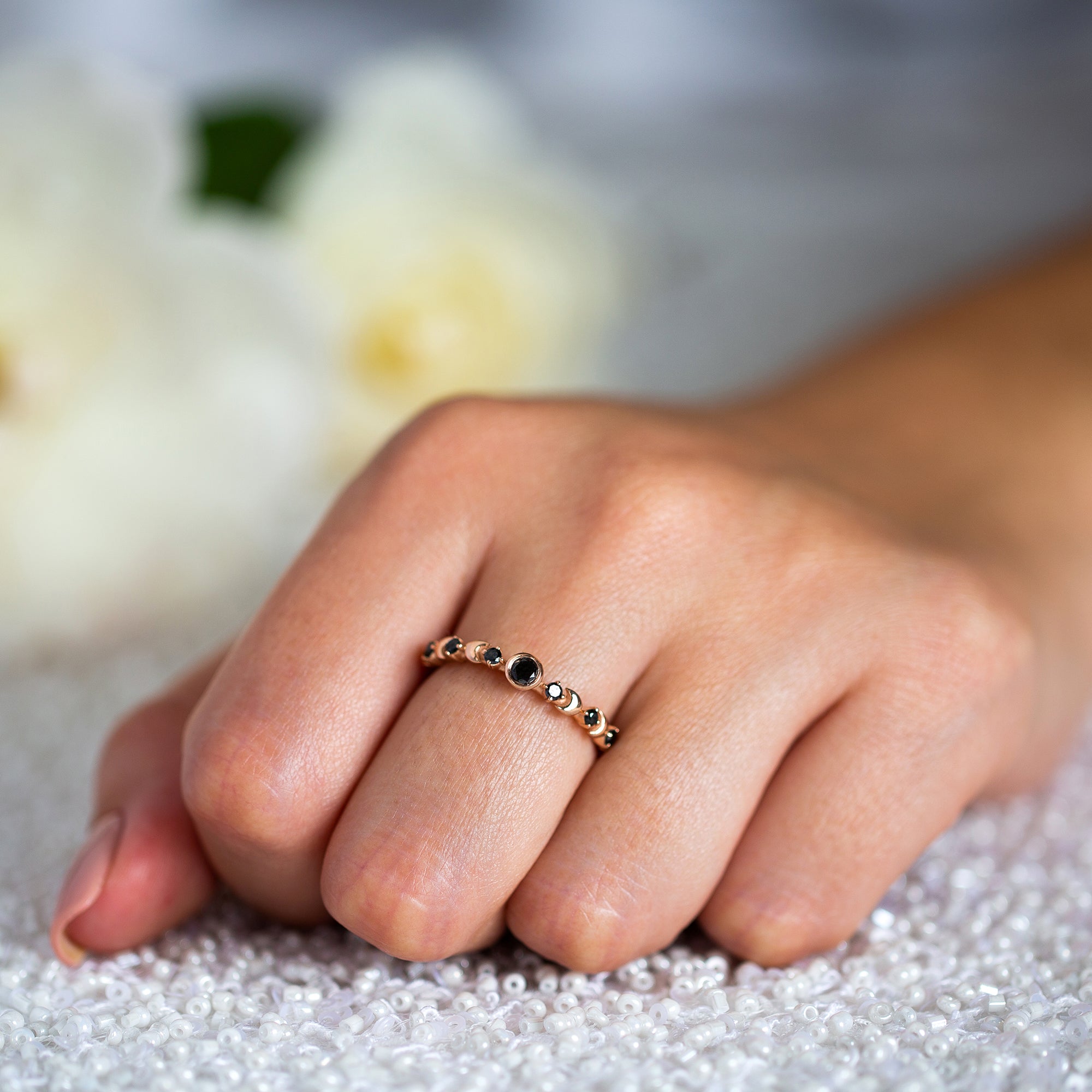 יד של אישה שעונדת טבעת יהלומים שחורים עדינה