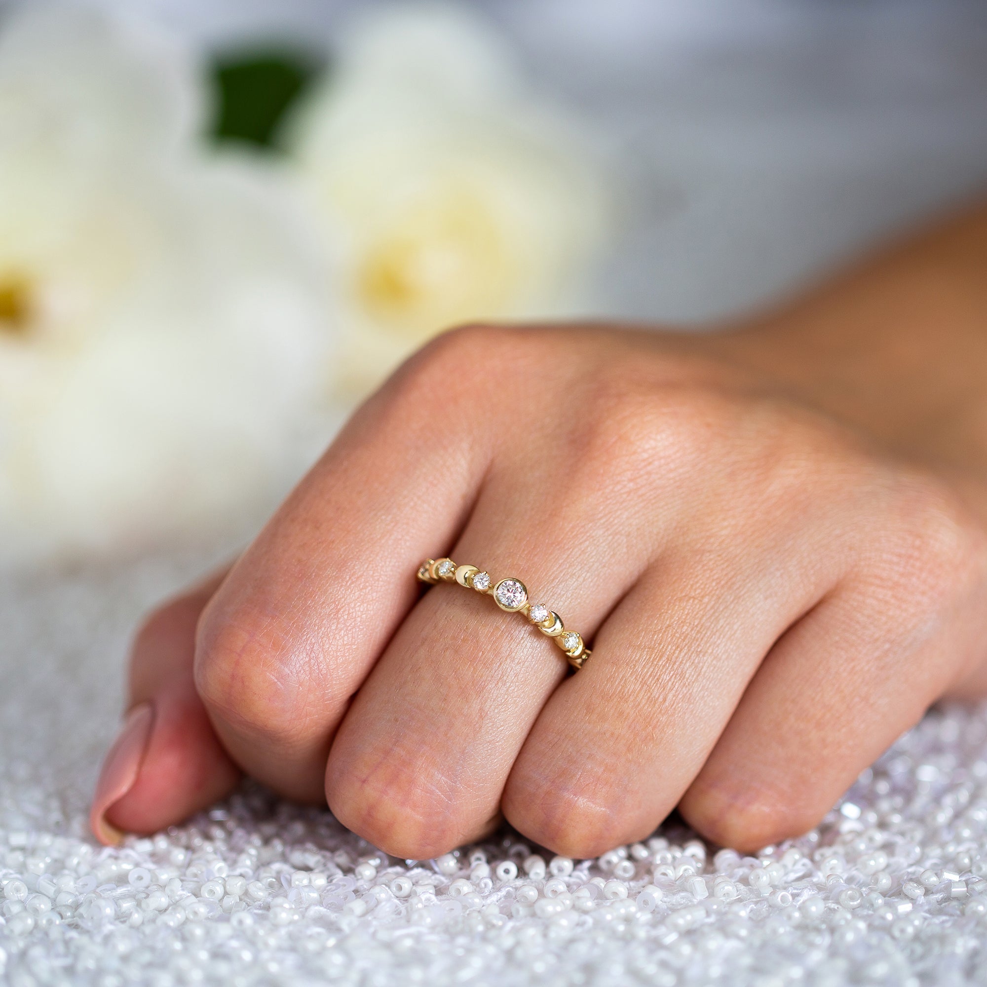 יד של אישה שעונדת טבעת אירוסין עדינה משובצת יהלומים לבנים בזהב 14 קראט צהוב