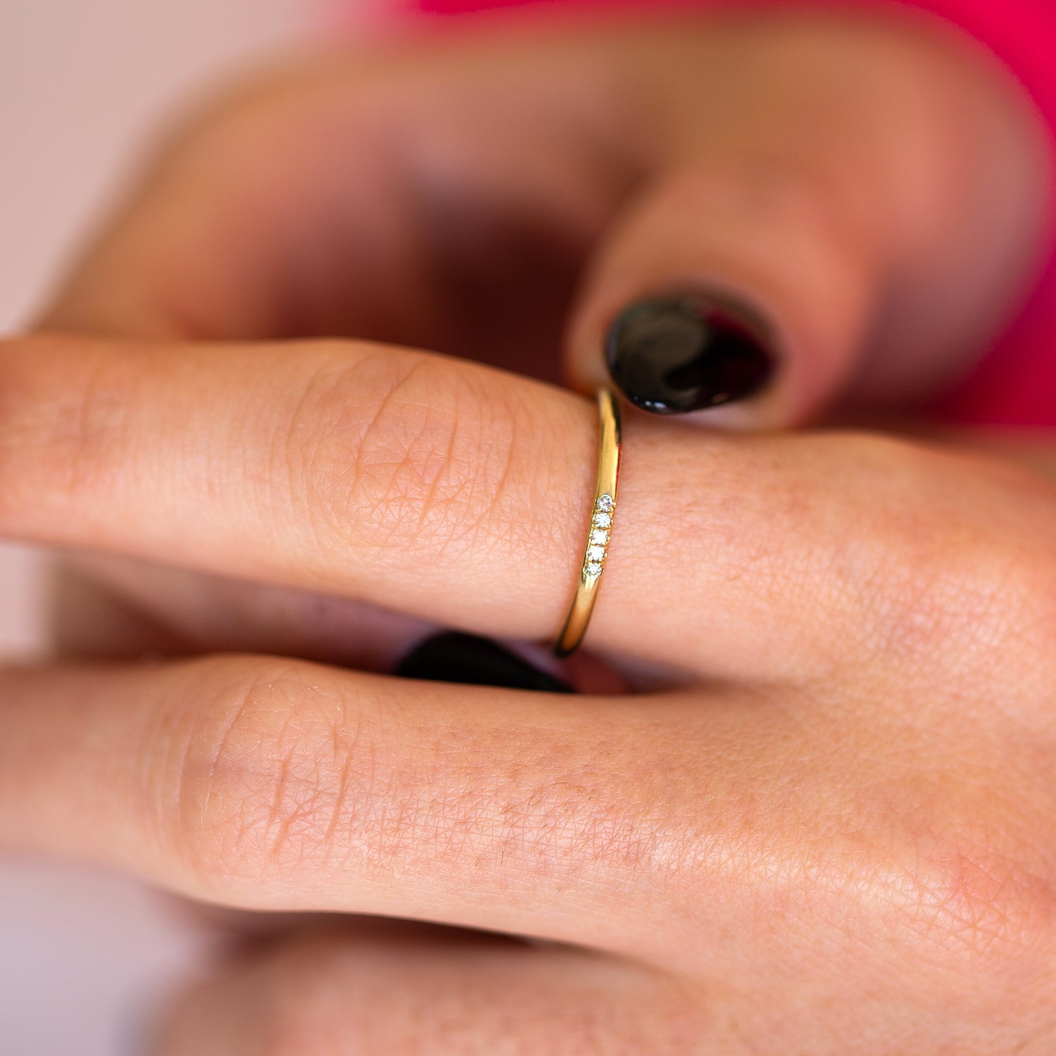 תקריב של אצבעות של אישה שעונדת טבעת זהב עדינה משובצת יהלומים