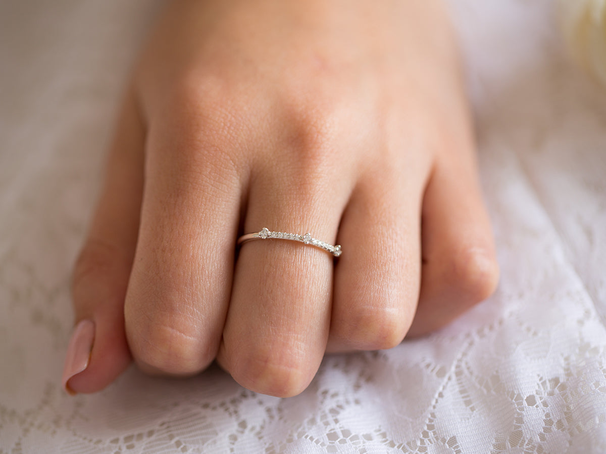 אישה עונדת טבעת יהלומים דקה ועדינה מזהב לבן 18 קראט בעיצוב מודרני ומיוחד