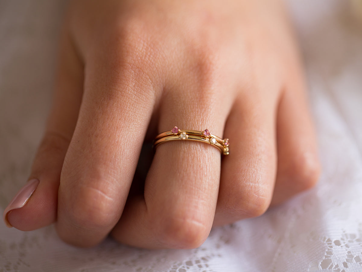 אישה עונדת סט טבעות זהב צהוב ואדום 18 קראט עדינות משובצות יהלומים וספירים ורודים