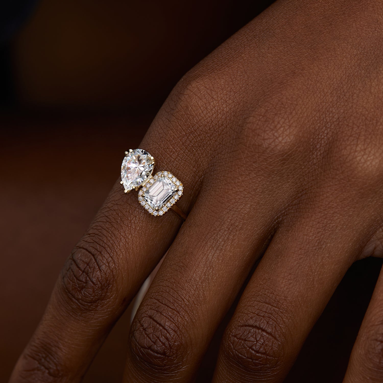 אישה עונדת טבעת אירוסין מרובעת משובצת שתי אבני מואסנייט ויהלומים