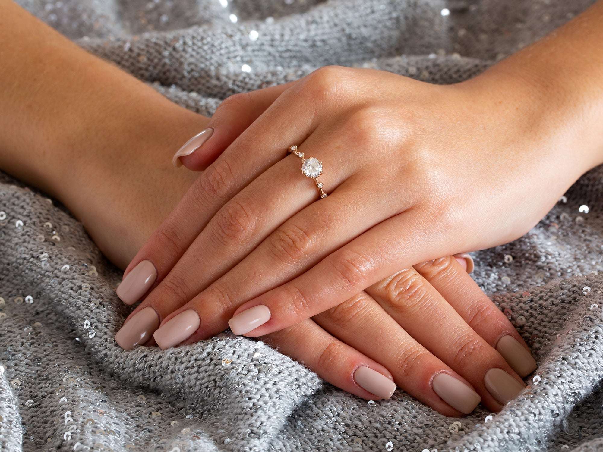 תקריב של יד של אישה עונדת טבעת אירוסין מיוחדת בזהב אדום משובצת יהלום טבעי