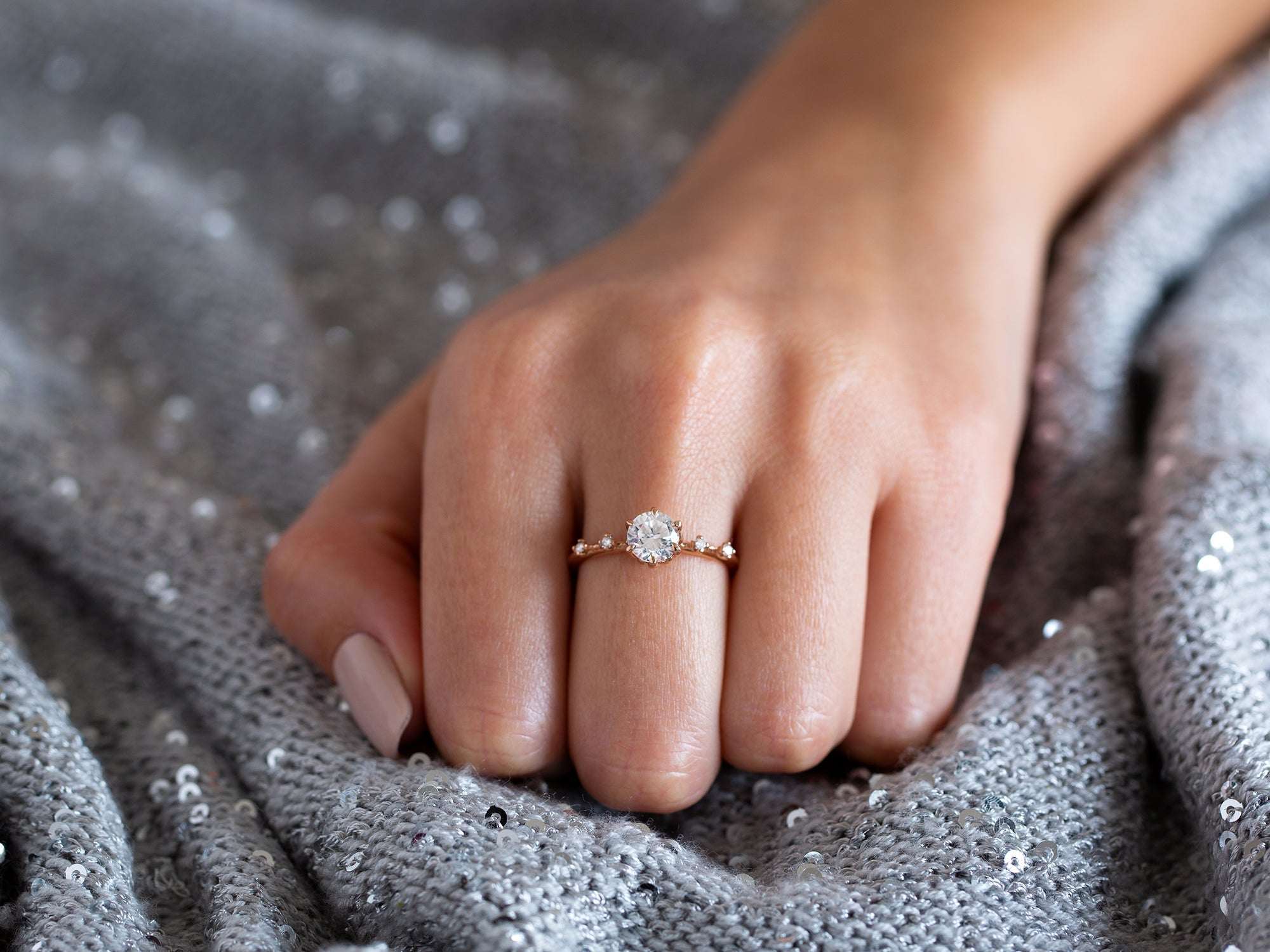 יד של אישה עונדת טבעת אירוסין בזהב 14 קראט אדום משובצת יהלומים