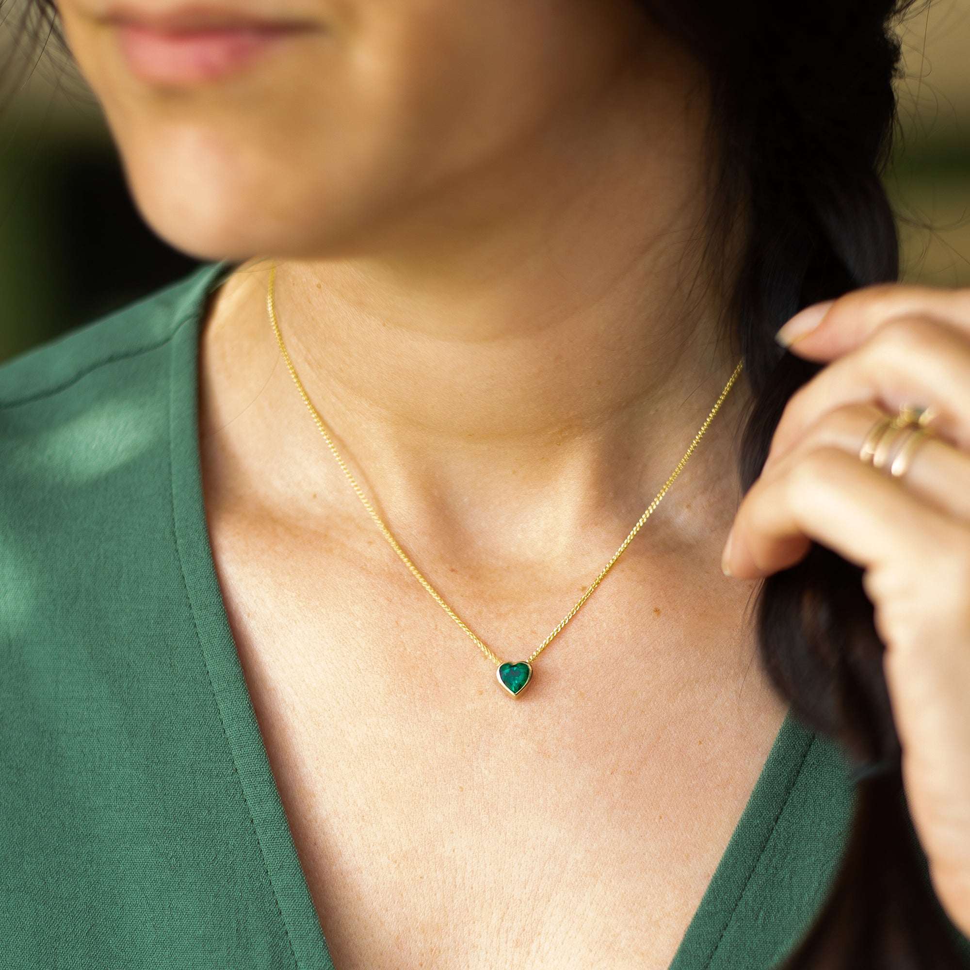 תקריב של תליון לב עם אמרלד ירוק על צוואר