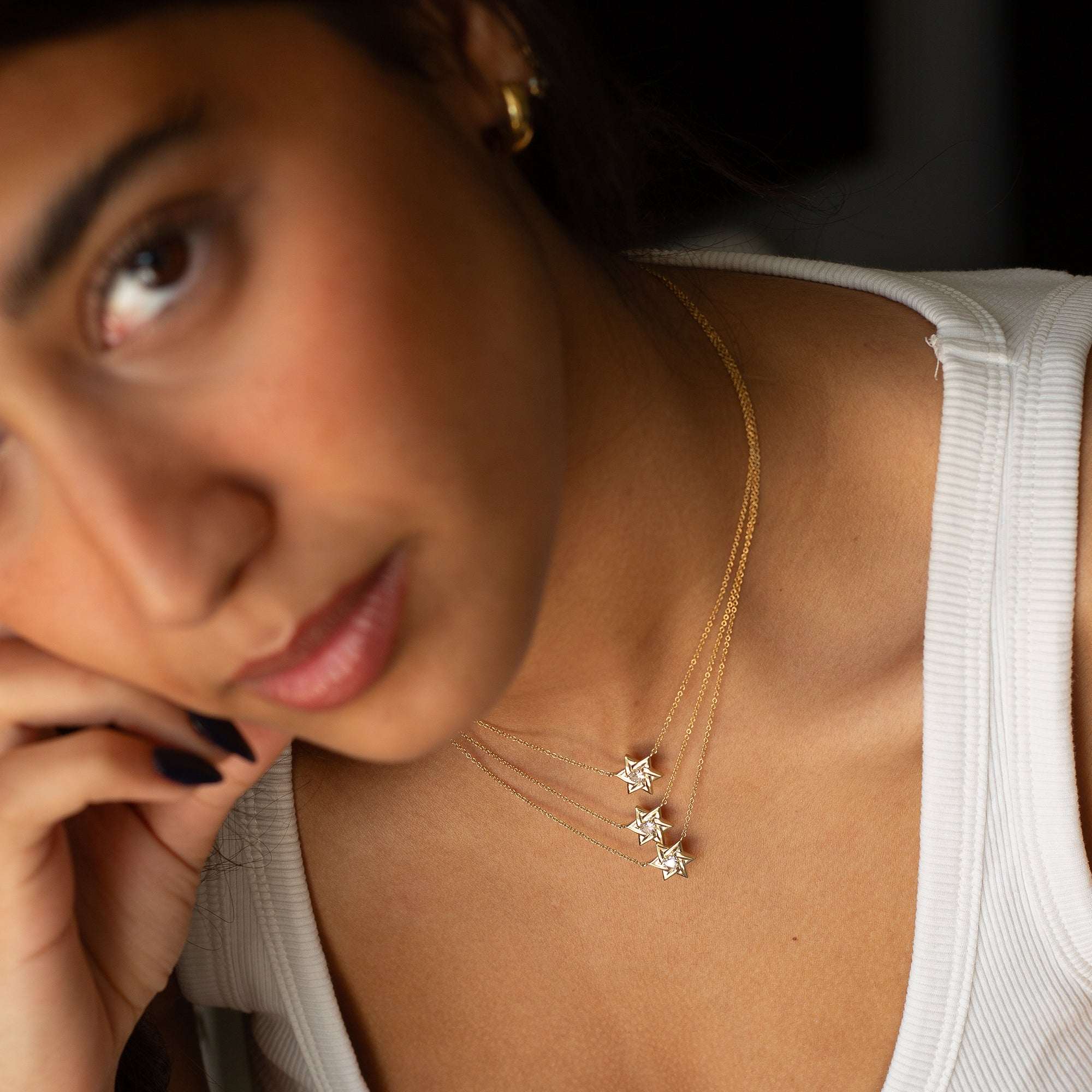 חצי פנים של אישה שעונדת שלוש שרשראות זהב צהוב עם תליון מגן דוד