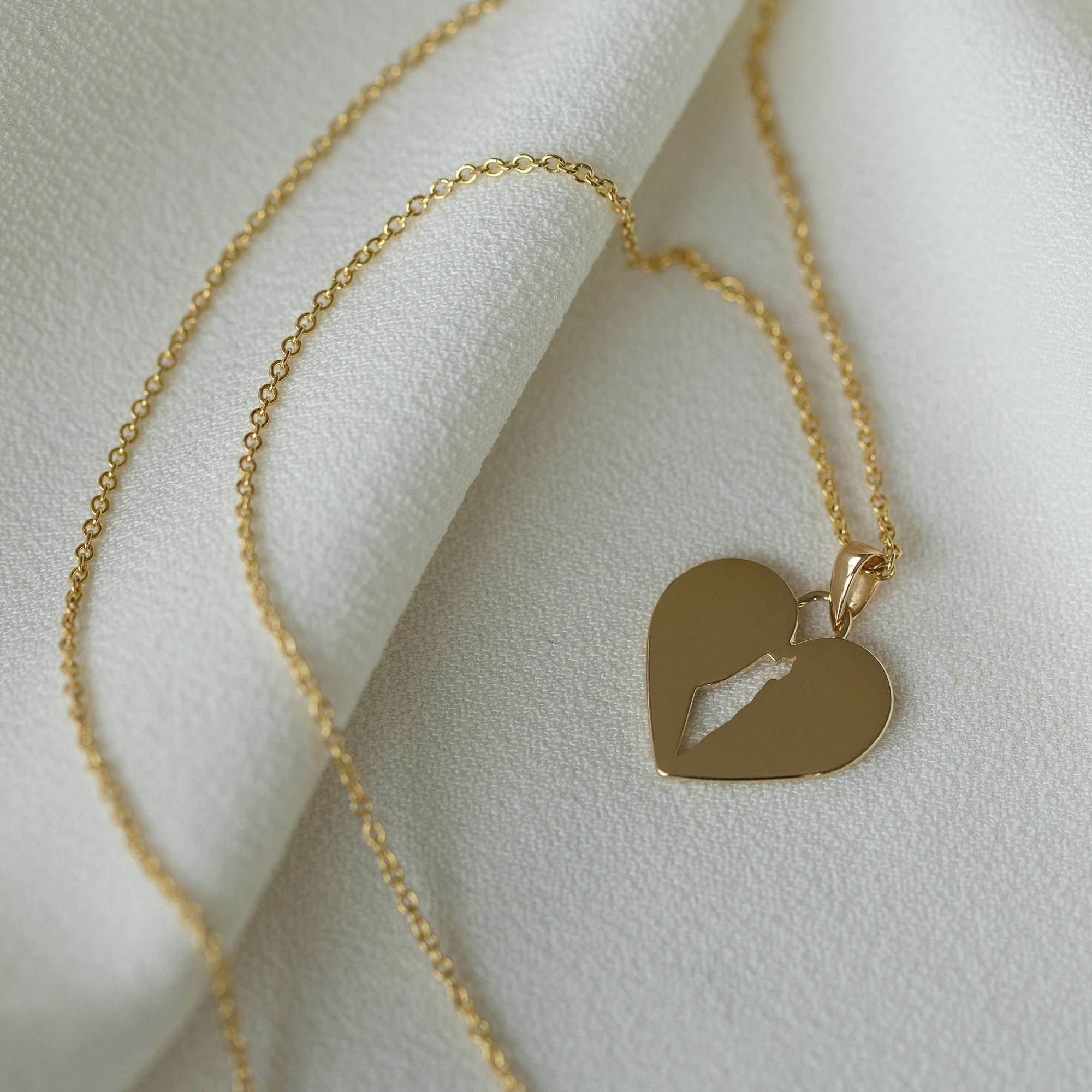 תקריב של שרשרת מפת ישראל בזהב צהוב על רקע בד לבן