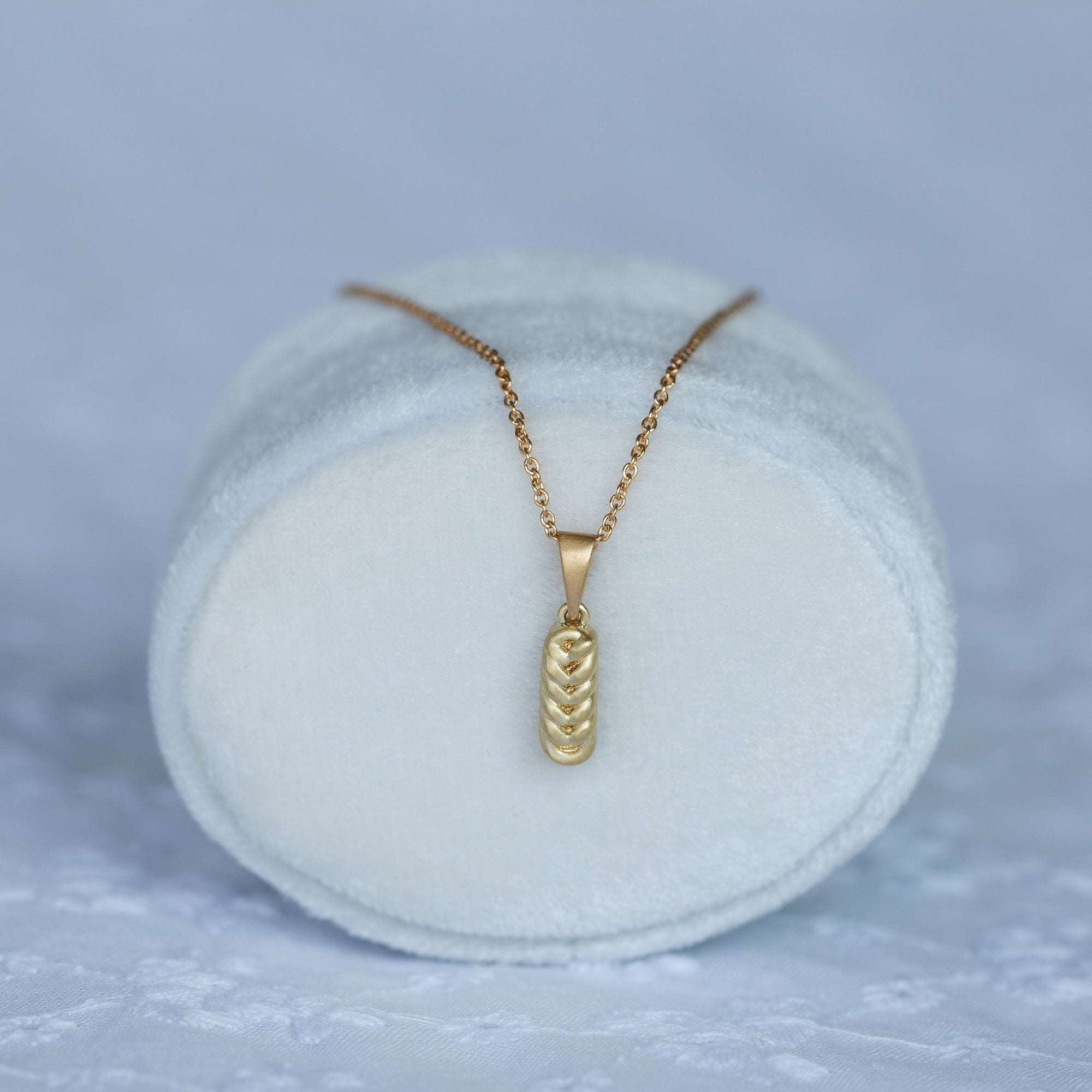 תקריב של שרשרת זהב דקה עם תליון חלה , מונחת על קופסת תכשיטים