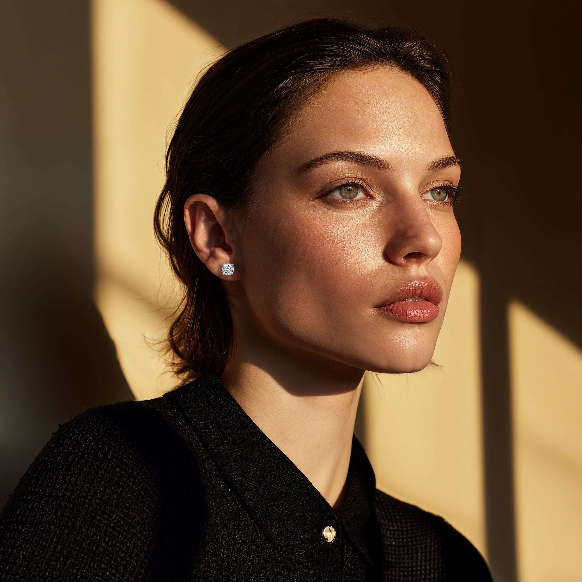 אישה עונדת עגילי יהלומים צמודים לאוזן ולובשת חולצה שחורה