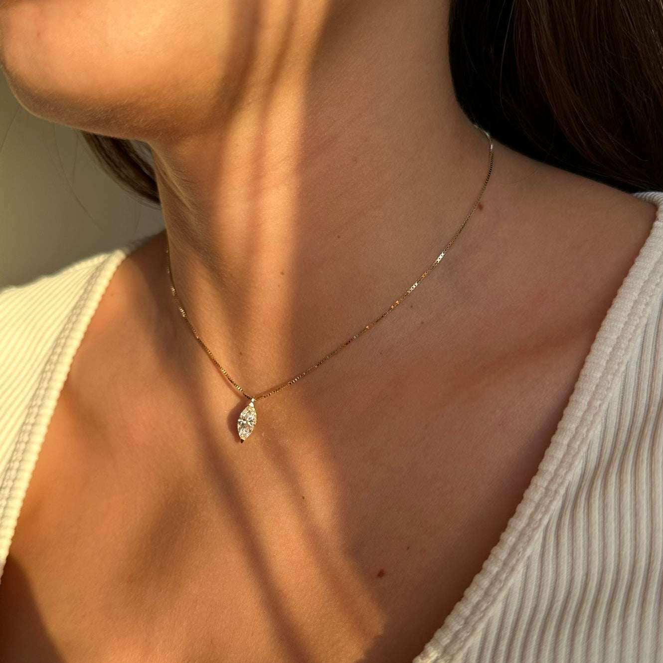 צוואר של אישה שעונדת שרשרת זהב עם יהלום מרקיזה בעיצוב נקי