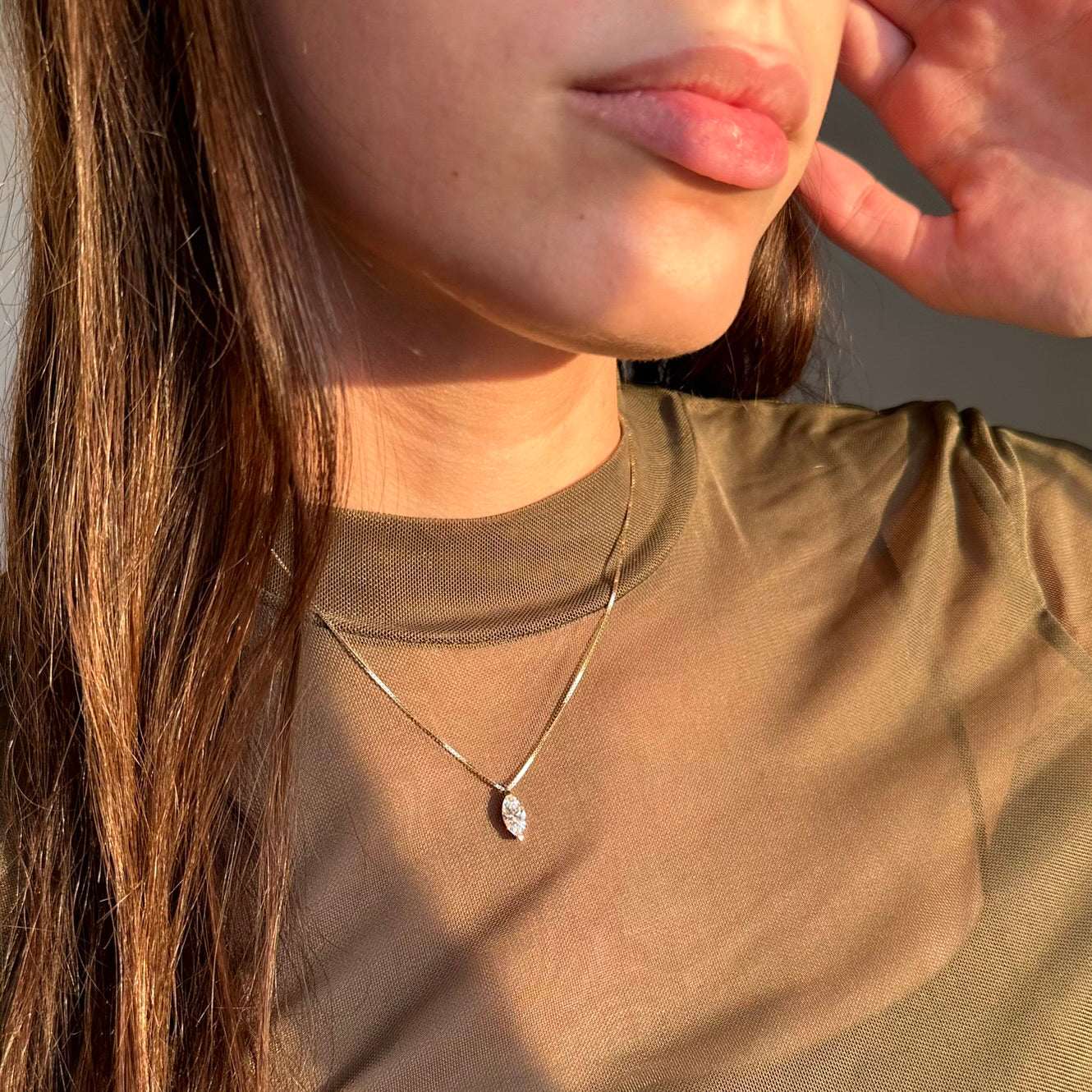 אישה עם חולצה ירוקה עונדת שרשרת זהב עדינה עם תליון יהלום בוהק