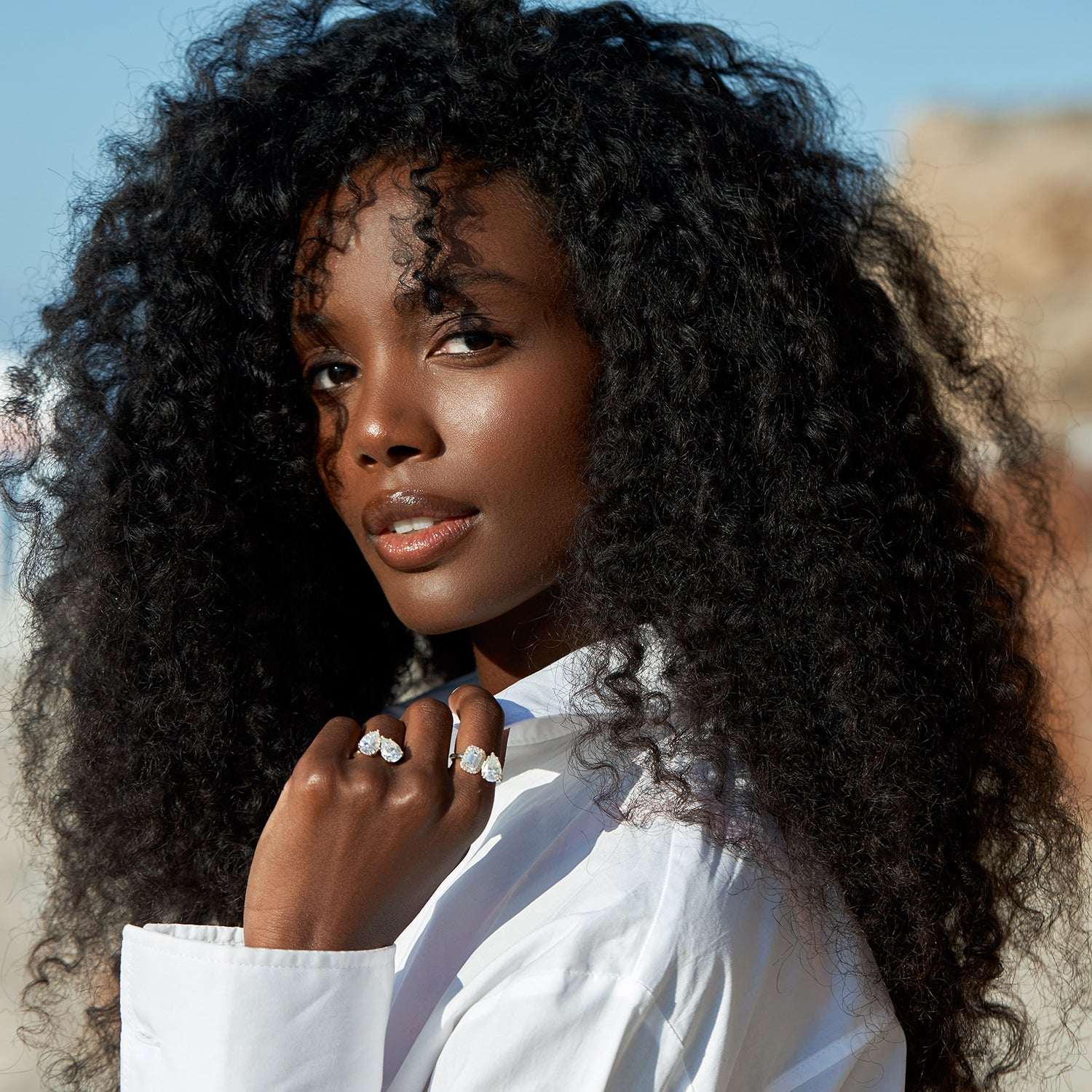 אישה עונדת שתי טבעות משובצות יהלום טיפה