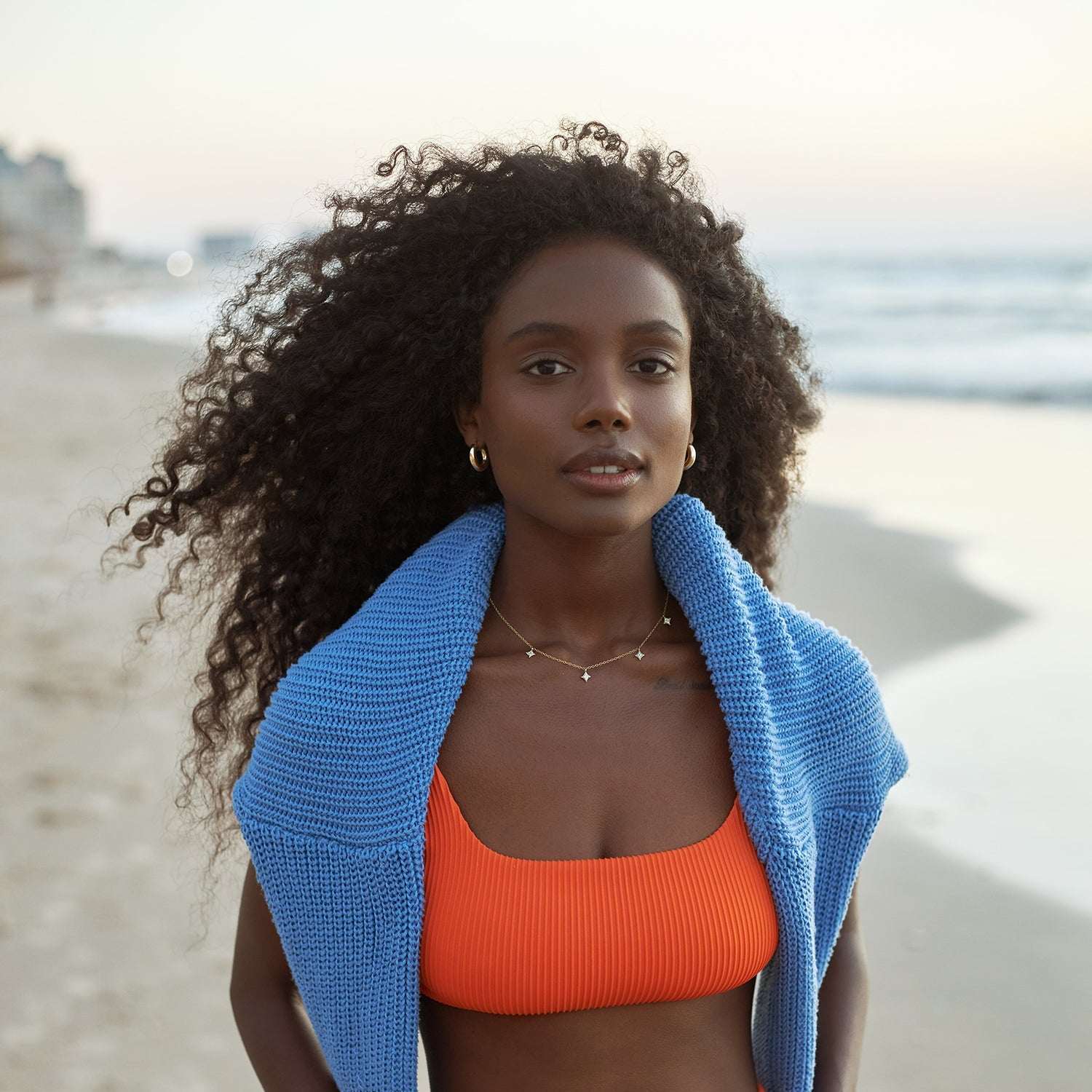 אישה עונדת שרשרת זהב מיוחדת עם כוכבים מושבצת יהלומים, סוודר כחול