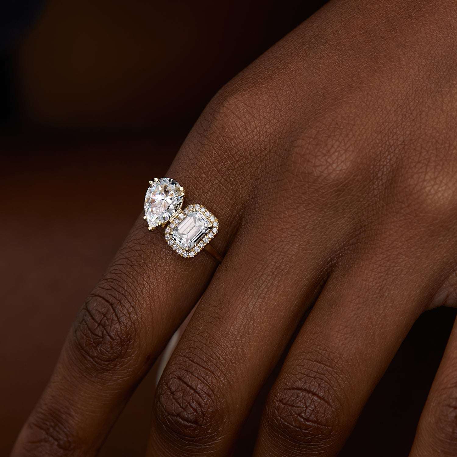 אישה עונדת טבעת אירוסין מרובעת משובצת שתי אבני מואסנייט ויהלומים