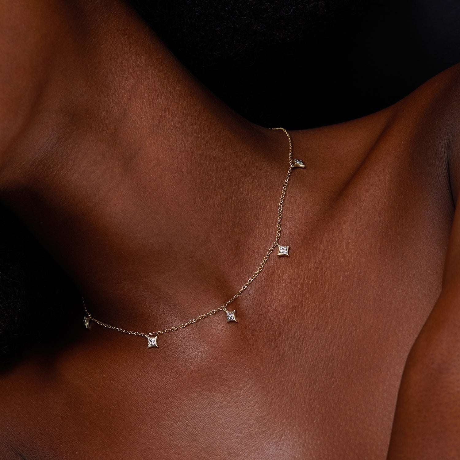 תקריב של צוואר של אישה שעונדת שרשרת זהב מיוחדת בעיצוב כוכבים