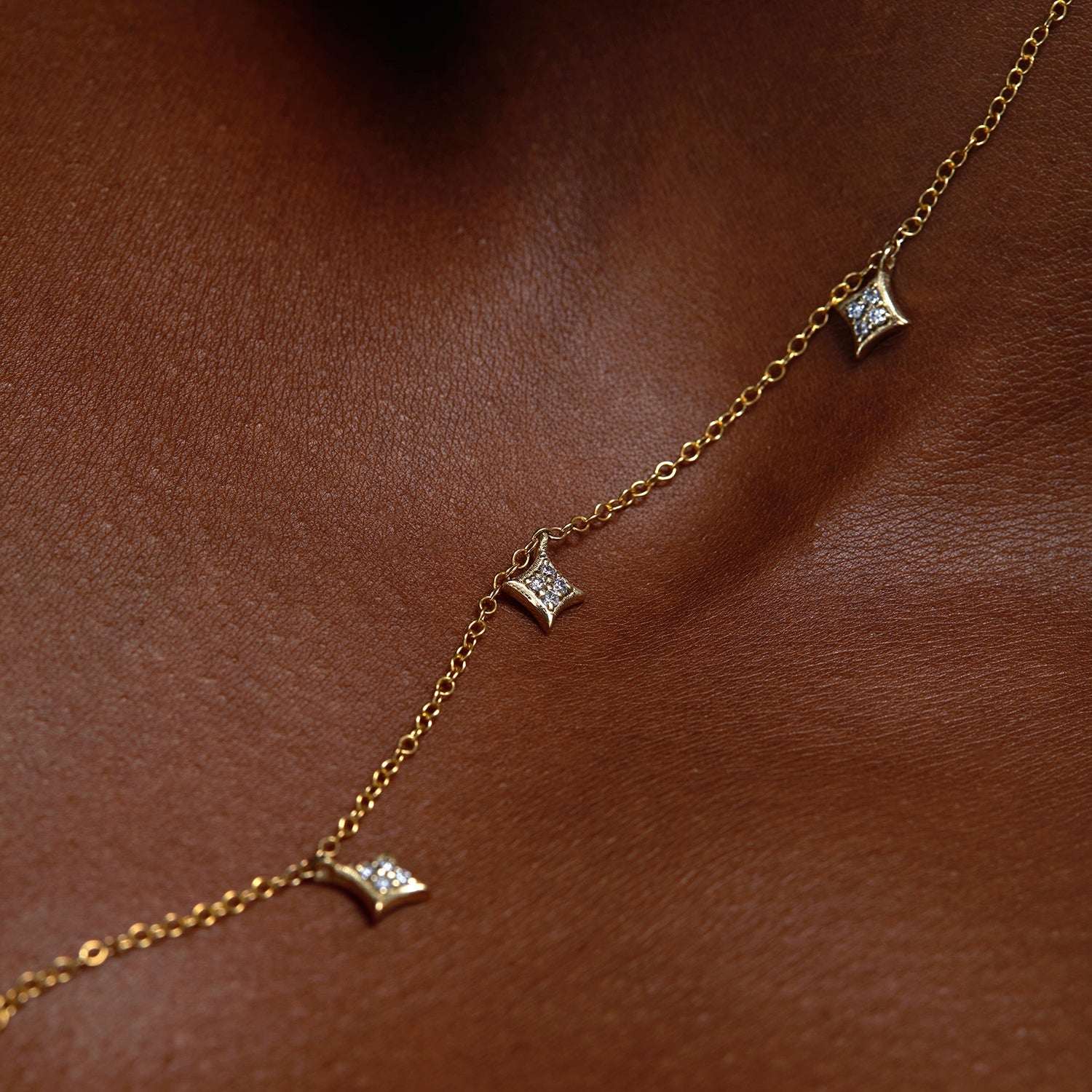 תקריב של שרשרת זהב מיוחדת עם תליוני כוכבים משובצים יהלומים