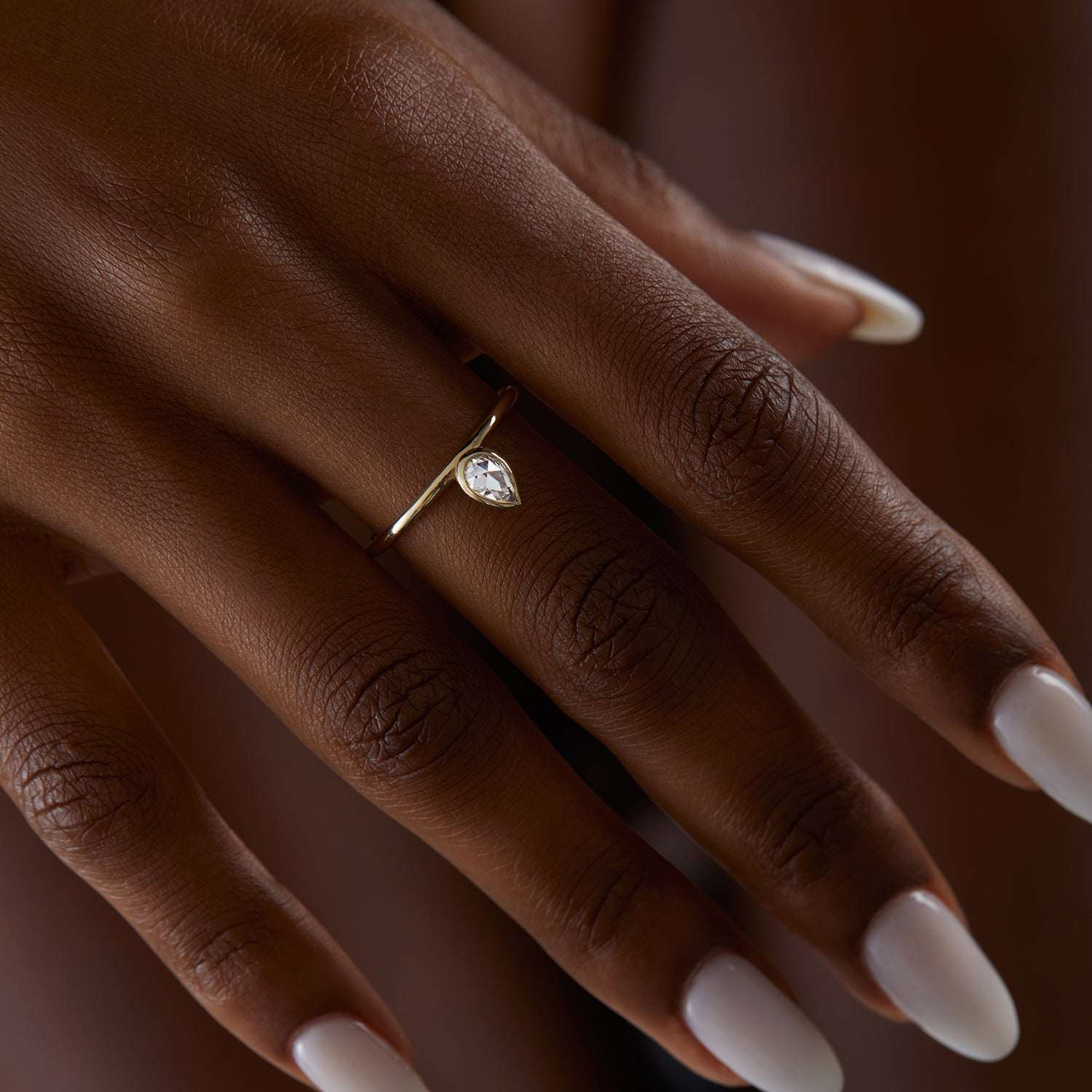 יד של אישה שעונדת טבעת מואסנייט טיפה בזהב צהוב 14 קראט