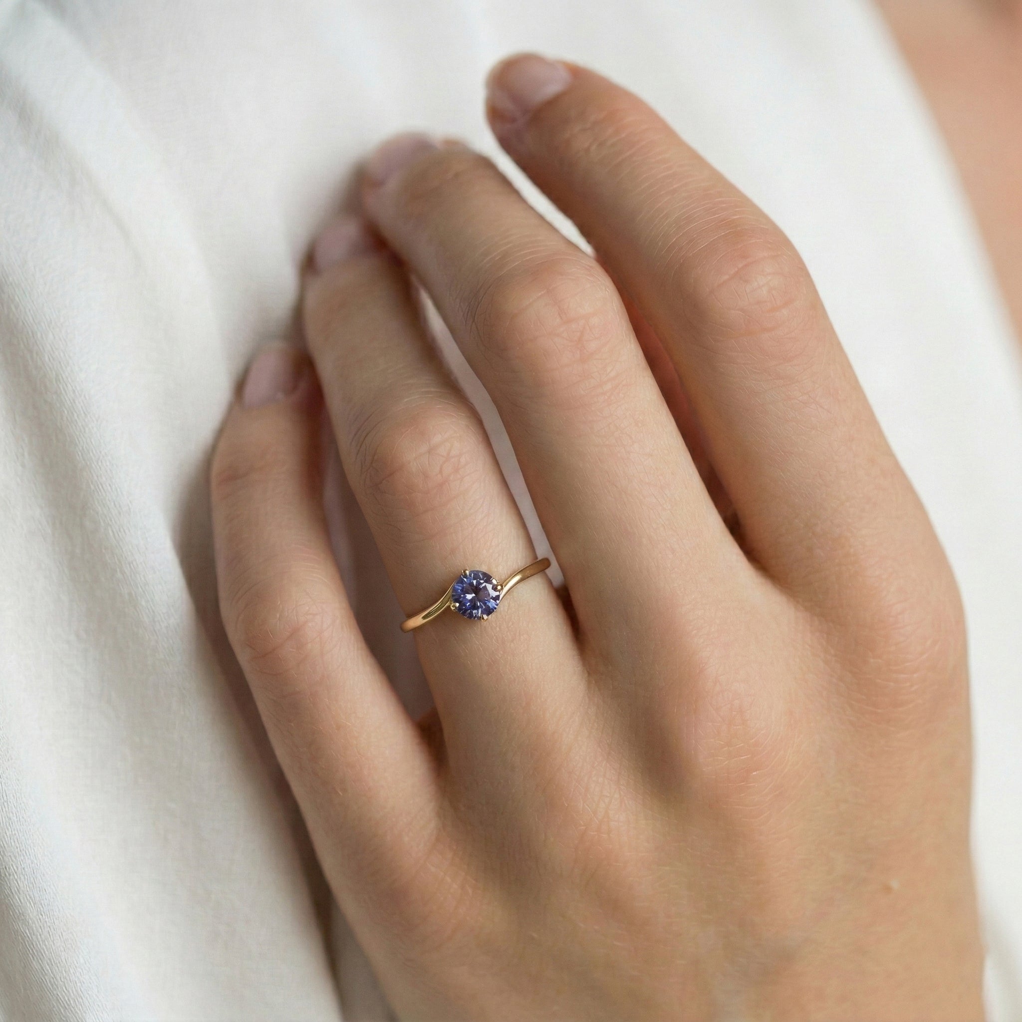 תקריב של יד של אישה שעונדת טבעת אלכסנדריט בזהב צהוב