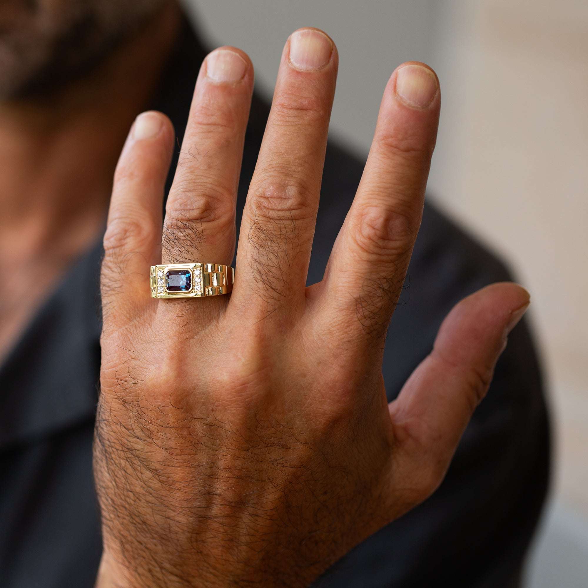 תקריב של יד של גבר שעונד טבעת חותם לגבר עם אלכסנדריט ויהלומים