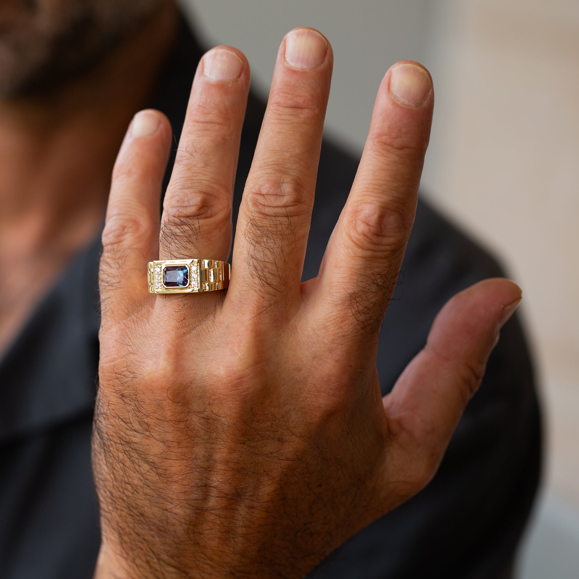 תקריב של יד של גבר שעונד טבעת חותם לגבר עם אלכסנדריט ויהלומים