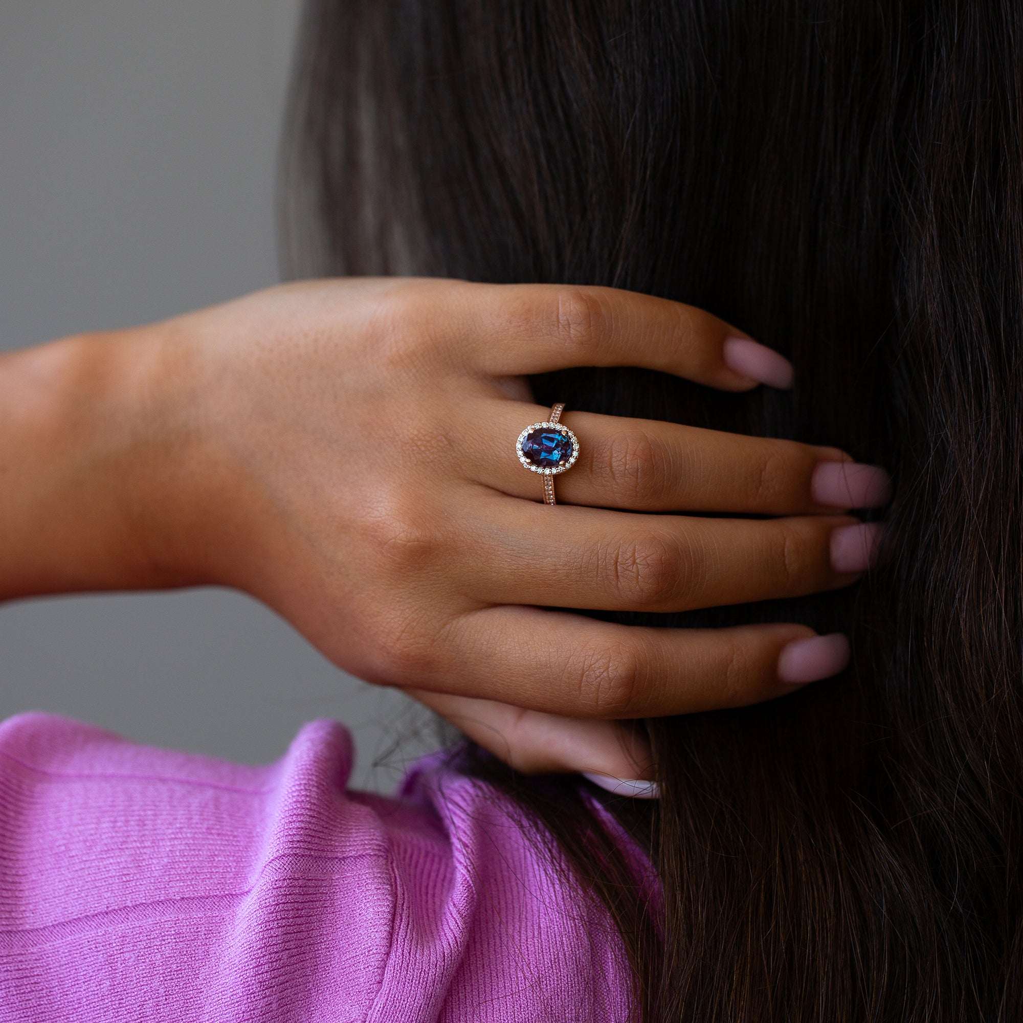 יד של אישה שעונדת טבעת משובצת אבן חן כחולה בזהב 14 קראט ויהלומי מעבדה