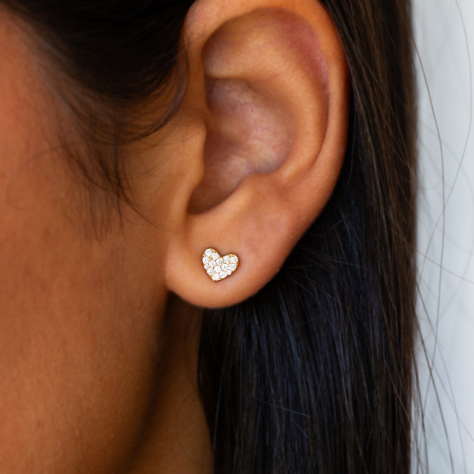 תקריב של אוזן של אישה שעונדת עגיל לב מזהב משובץ יהלומים