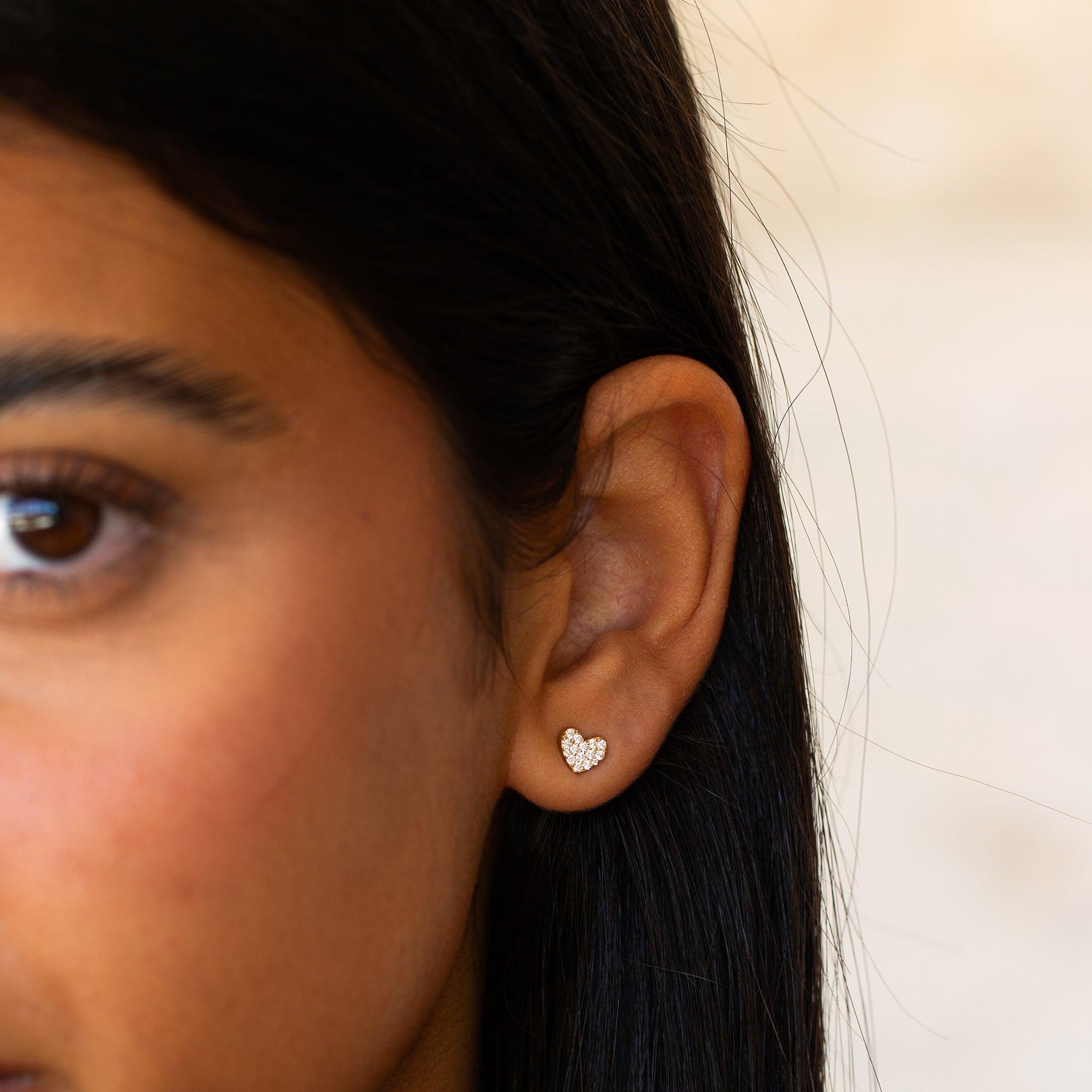 תקריב של פנים של בחורה שעונדת עגיל לב מזהב