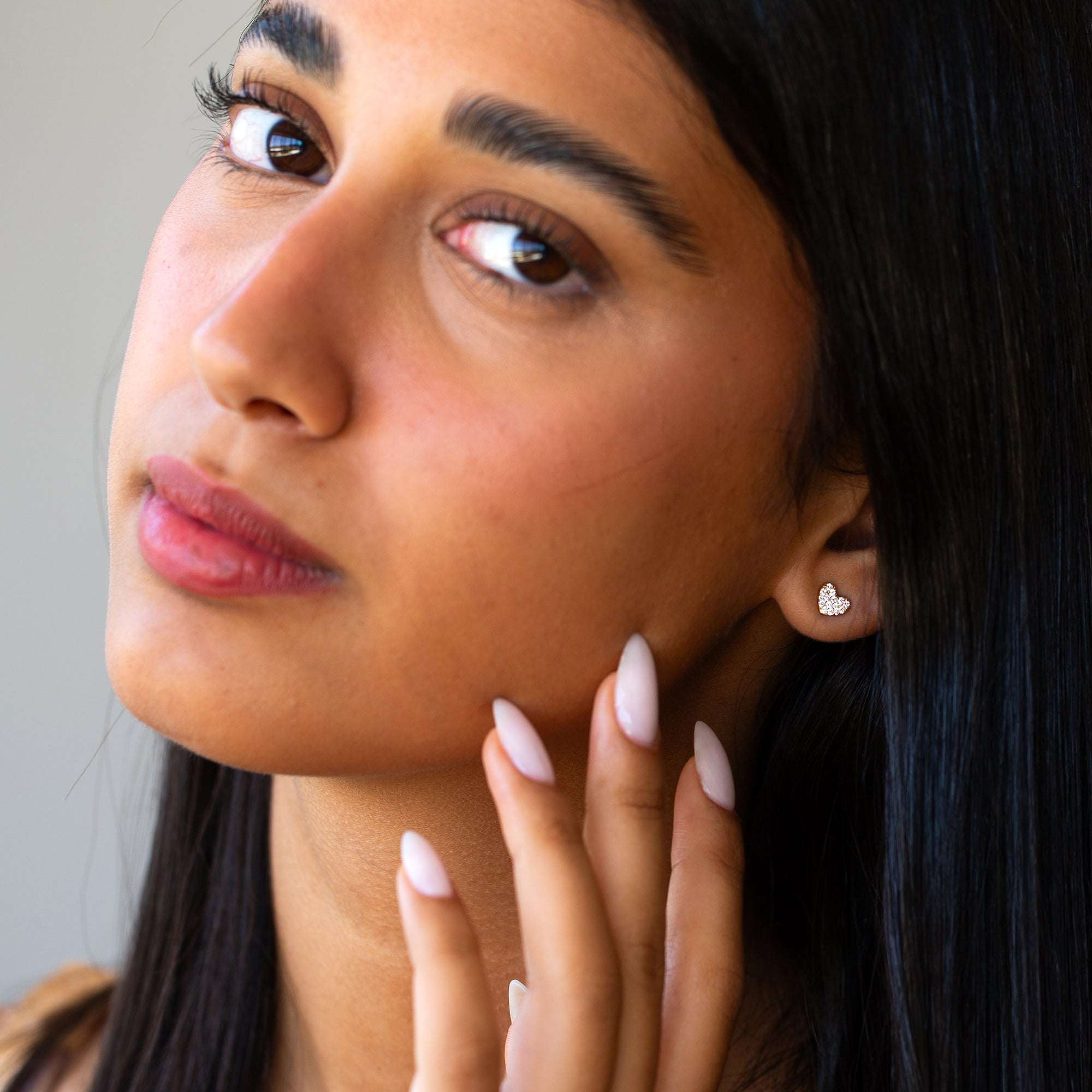 פנים של אישה שעונדת על האוזן עגיל לבבות משובץ יהלומים