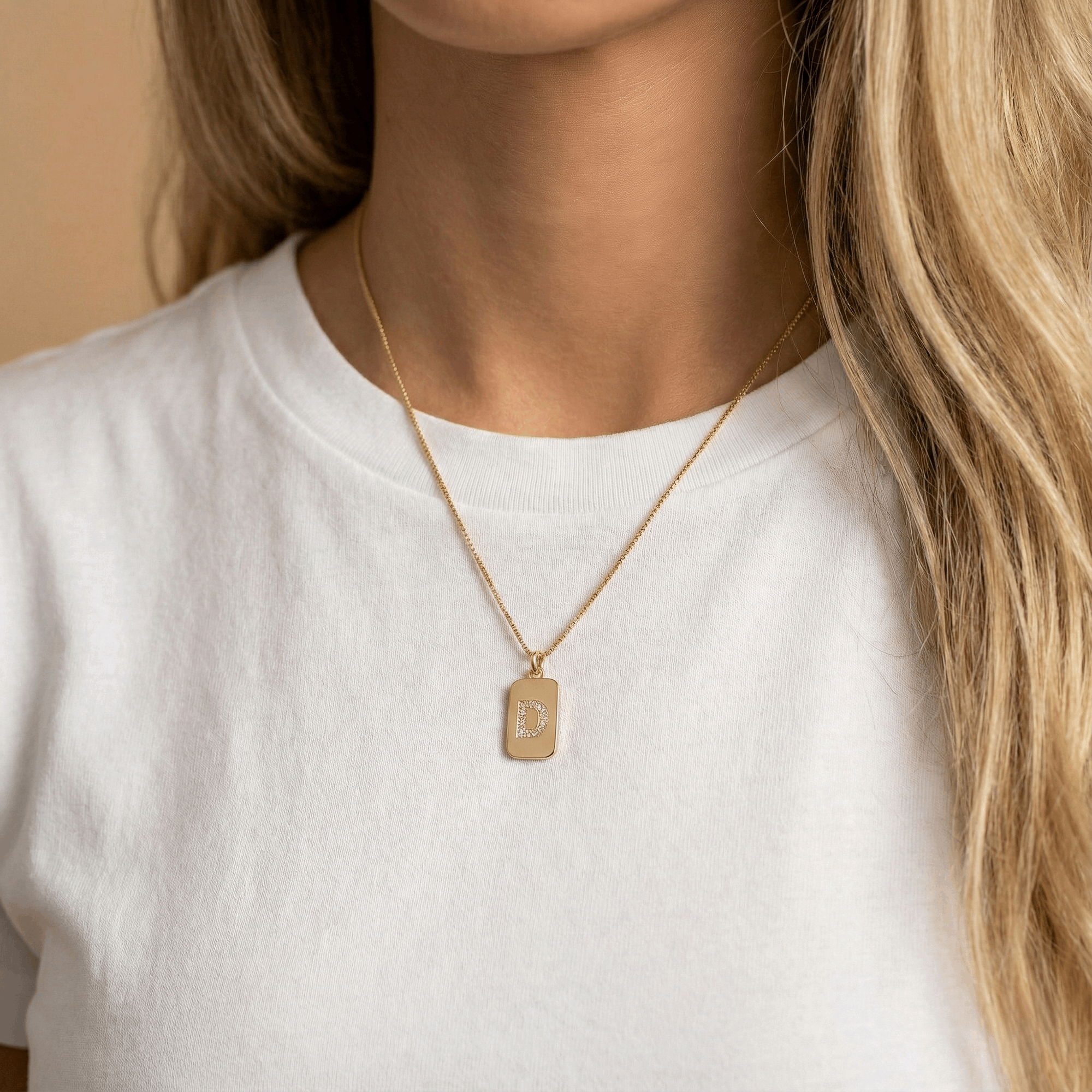 אישה עונדת שרשרת זהב עם תליון אות באנגלית משובצת יהלומים 