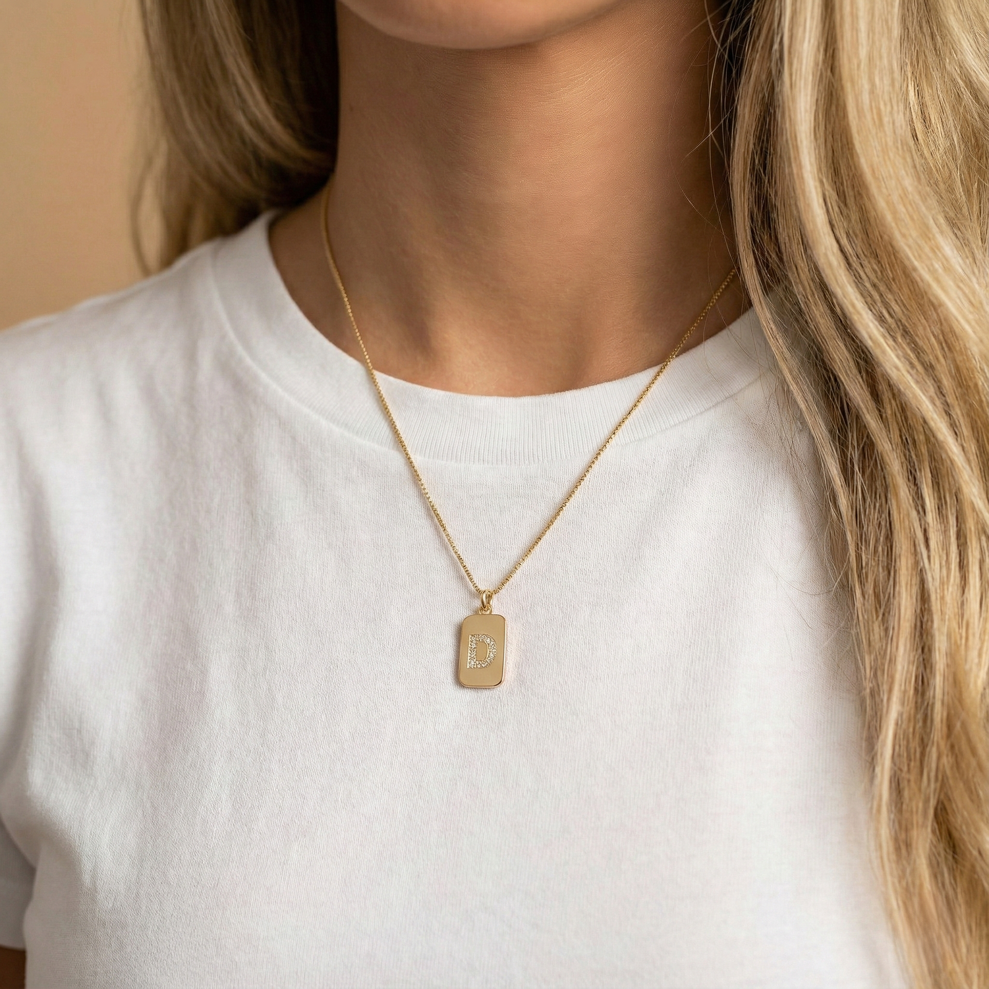 אישה עונדת שרשרת זהב עם תליון אות באנגלית משובצת יהלומים 