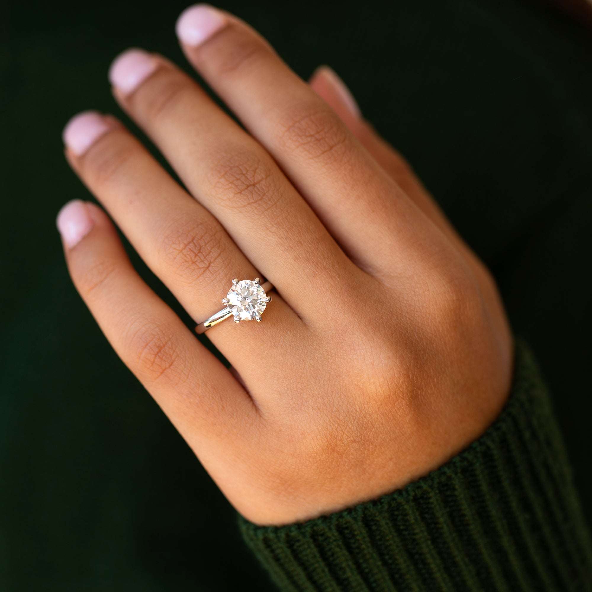 תקריב של יד של אישה עונדת טבעת סוליטר קלאסית משובצת יהלום מעבדה במשקל 2 קראט