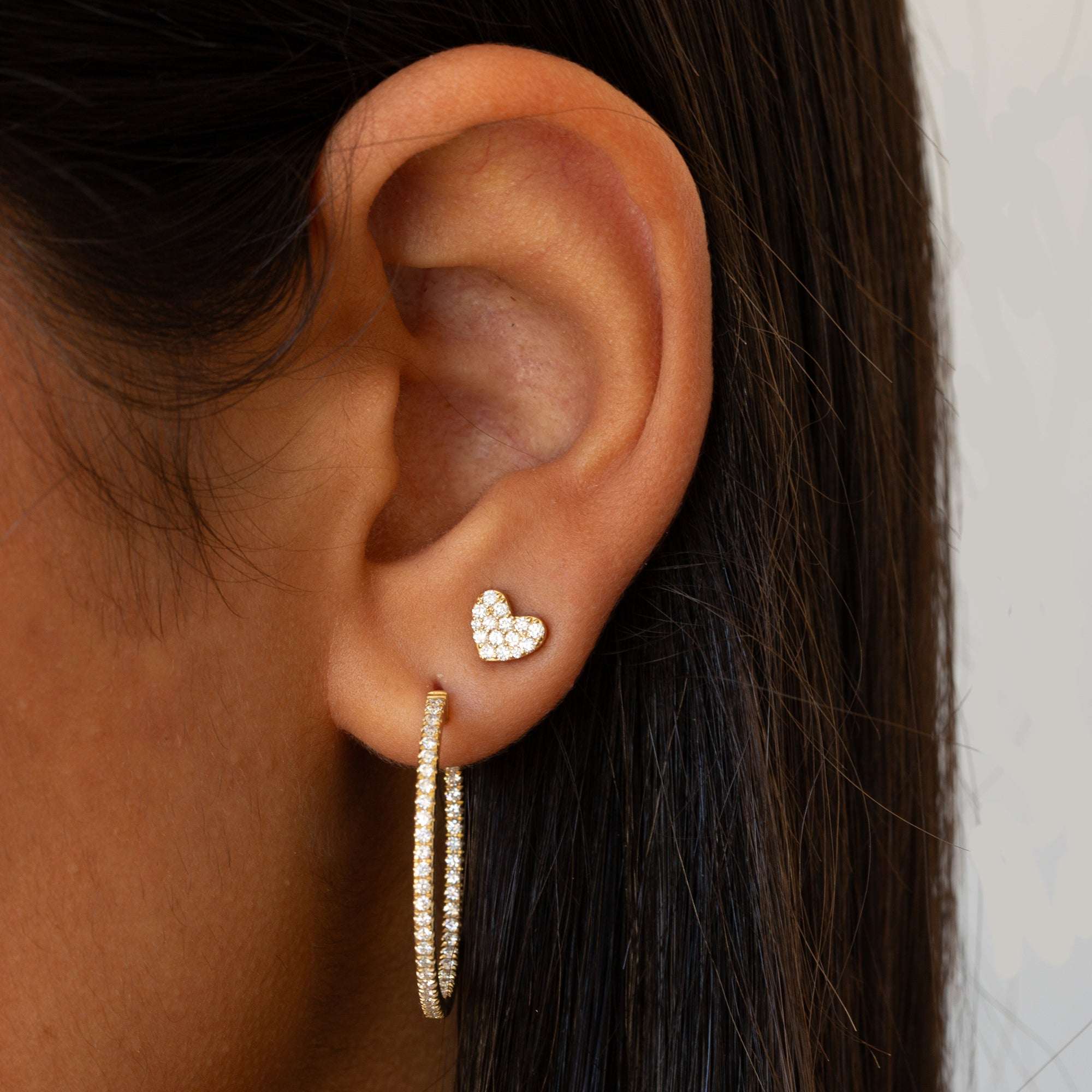 תקריב של אוזן של אישה שעונדת עגילי חישוק משובצים ועגיל לב משובץ