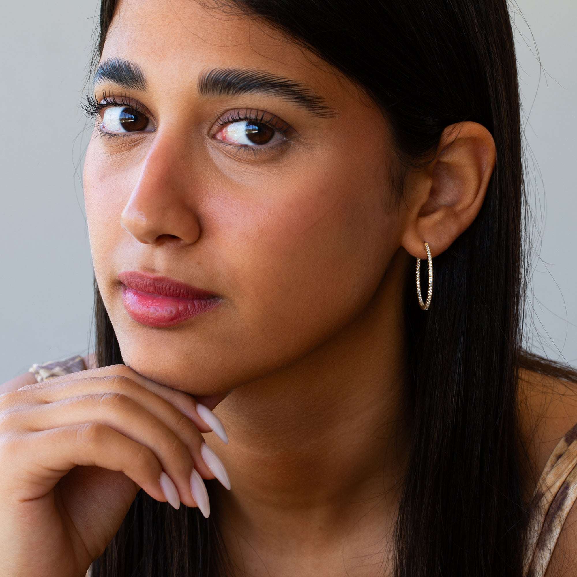 תקריב של אישה שעונדת עגילי חישוק מזהב משובצים יהלומים