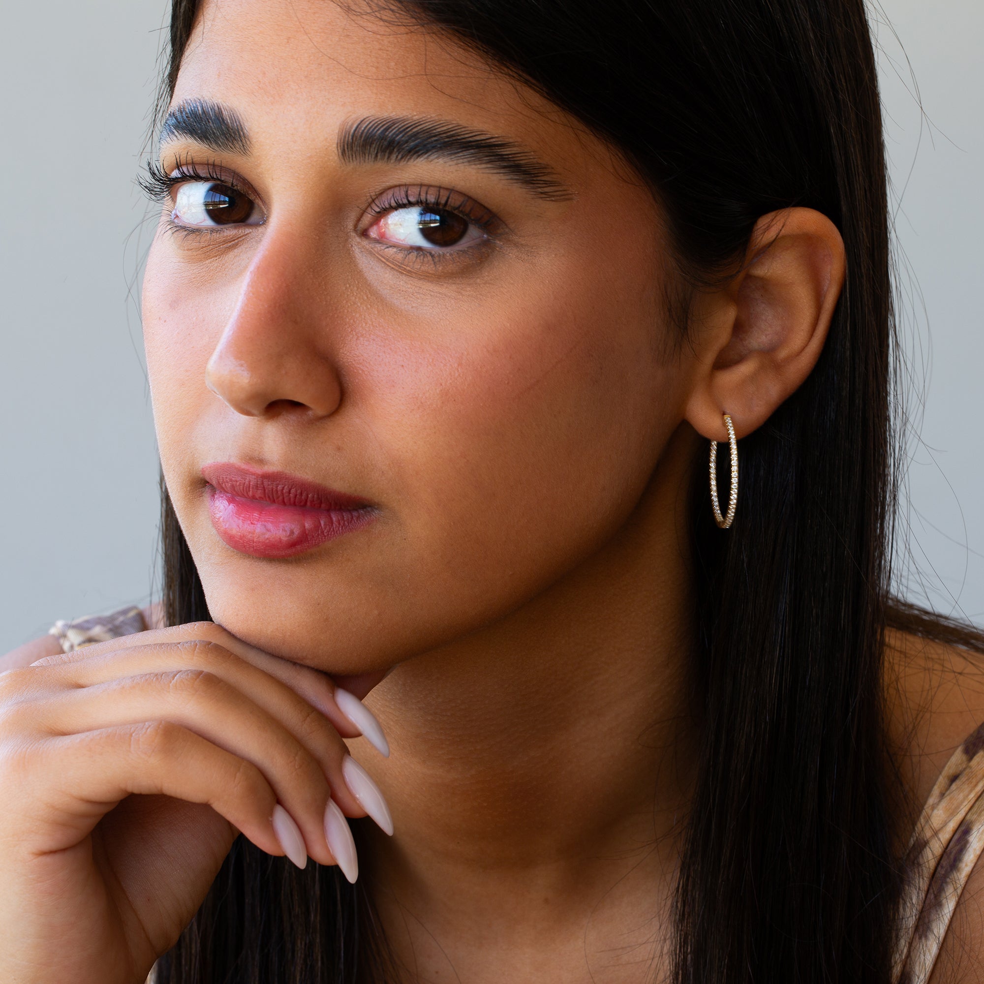 תקריב של אישה שעונדת עגילי חישוק מזהב משובצים יהלומים