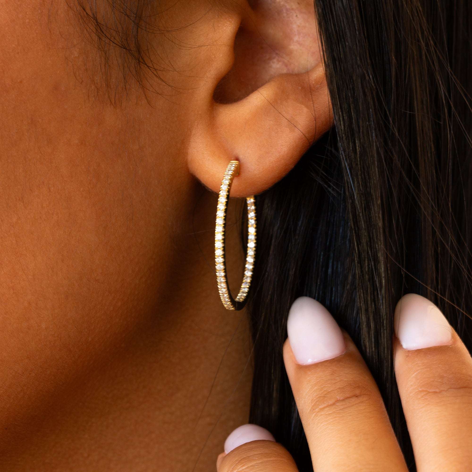 תקריב של אוזן שעונדת עגילי חישוק יהלומים גדולים